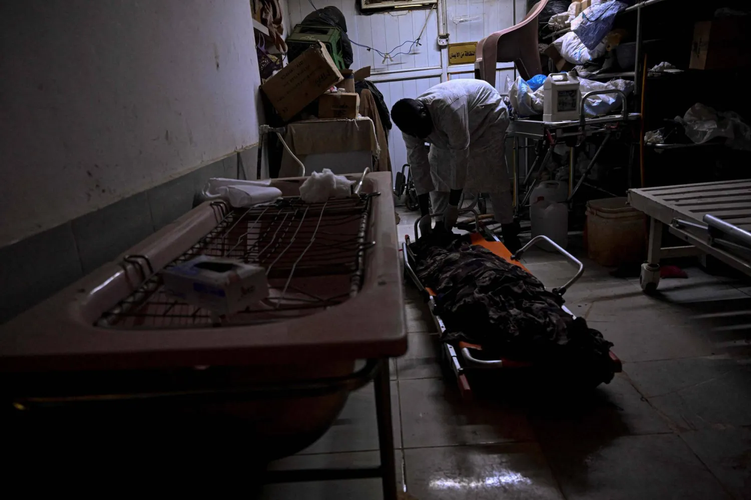 This photo taken on April 18, 2026 shows Sudanese Ali Gebbai, a volunteer responsible for handling burial procedures for unidentified bodies in the capital, Khartoum, examines one of the unidentified corpses at the mortuary of Omdurman's Al-Nao Educational Hospital. (AFP)