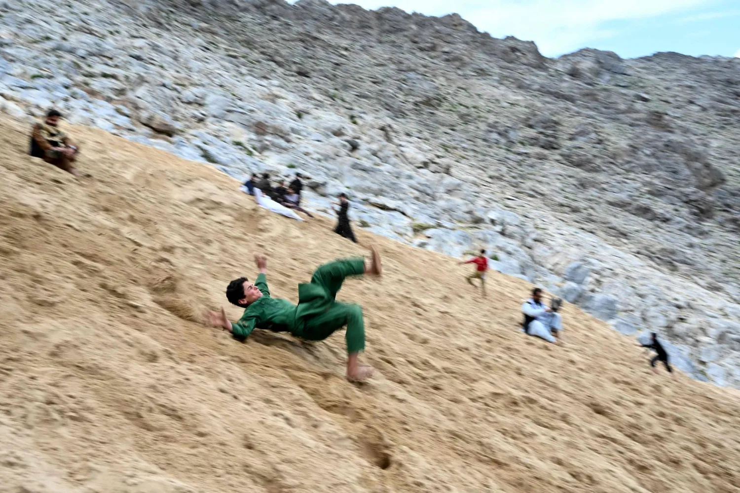 An Afghan boy enjoys rolling down a steep and sandy mountainside on a weekend at the Sayad area of Reg-e-Rawan in Kapisa province on April 24, 2026. (AFP)
