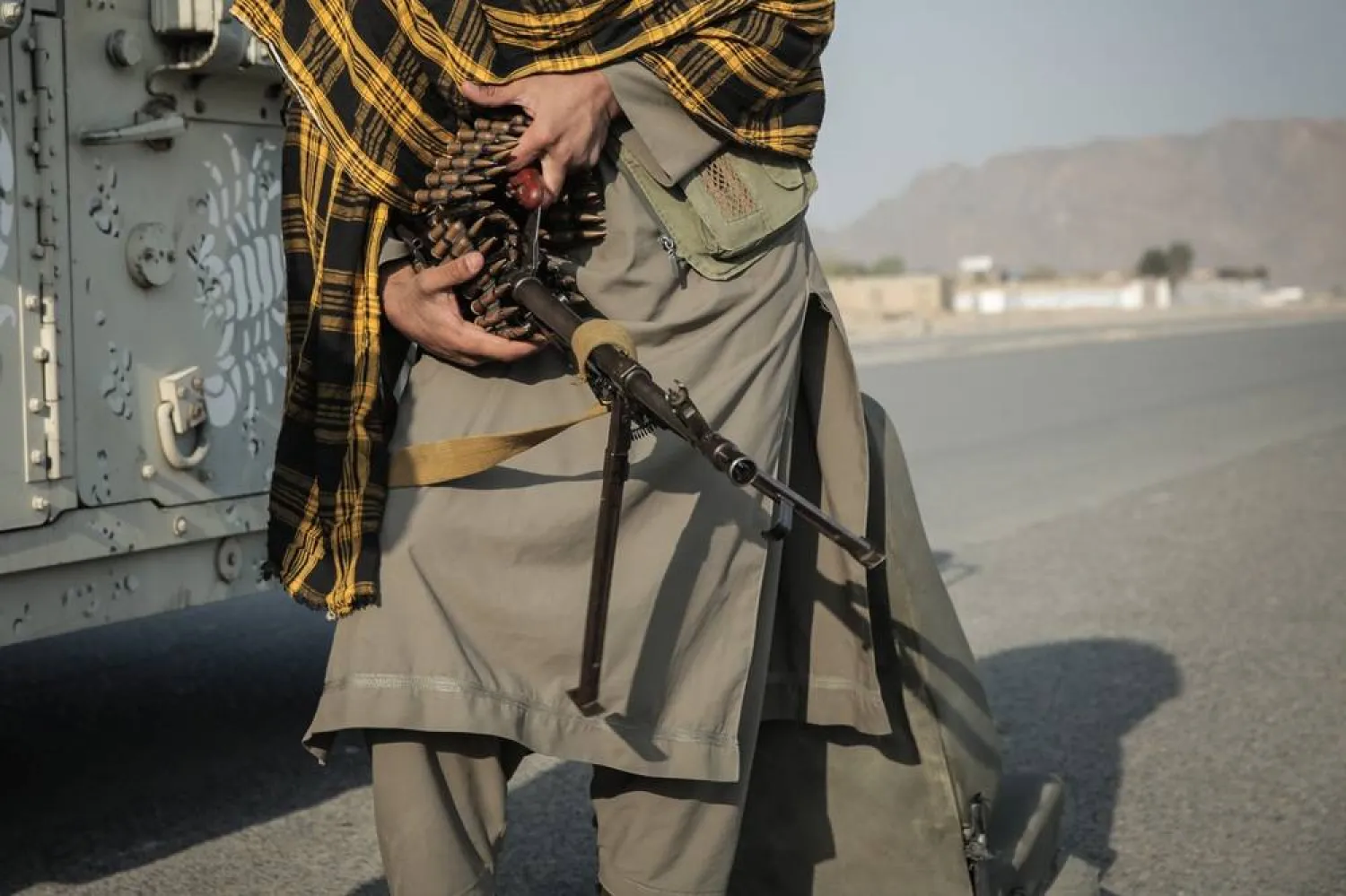 28 February 2026, Afghanistan, Torkham: A Taliban fighter checks his weapon next to an armored vehicle at a checkpoint near Torkham border crossing between Pakistan and Afghanistan. (dpa)