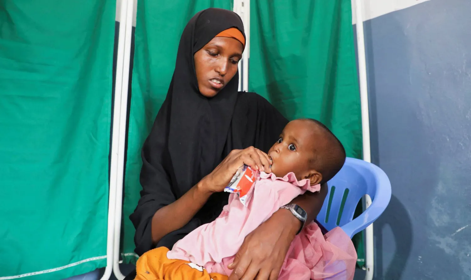 Fatima Mohamed feed Iqlas Omar Abdi, 1, with nutritious supplementary biscuit at the Daynile hospital as shortages of lifesaving therapeutic foods caused by shipping disruptions due to the Iran war have forced clinics treating severely malnourished children to turn away patients and ration supplies in drought-hit Somalia, in Daynile district of Mogadishu, Somalia April 20, 2026. (Reuters)