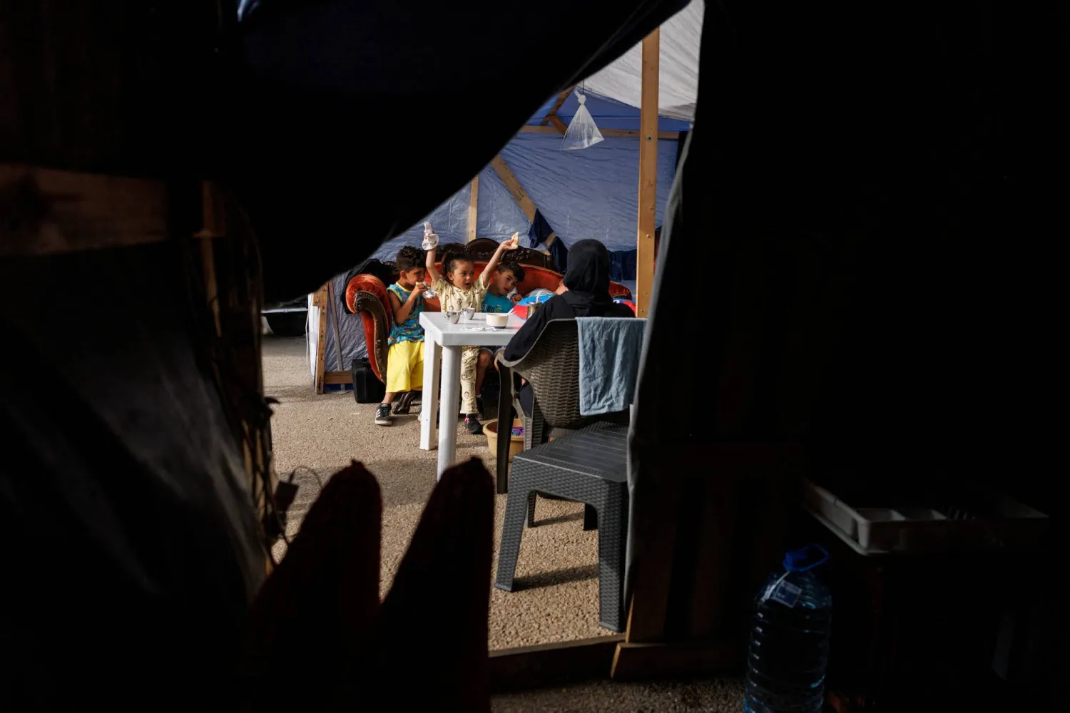 أطفال ربيع خريس يتناولون وجبة الإفطار أثناء جلوسهم في مأواهم داخل مخيم مؤقت في بيروت (رويترز)