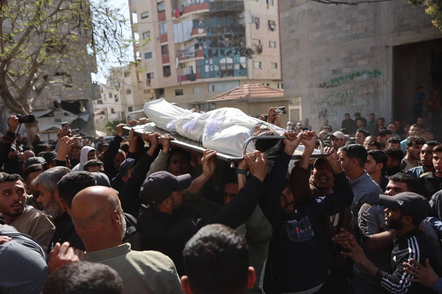 فلسطينيون نازحون يحملون جثماناً خلال جنازة أربعة أشخاص قُتلوا في غارة إسرائيلية استهدفت سيارة بمدينة غزة (أ.ف.ب)