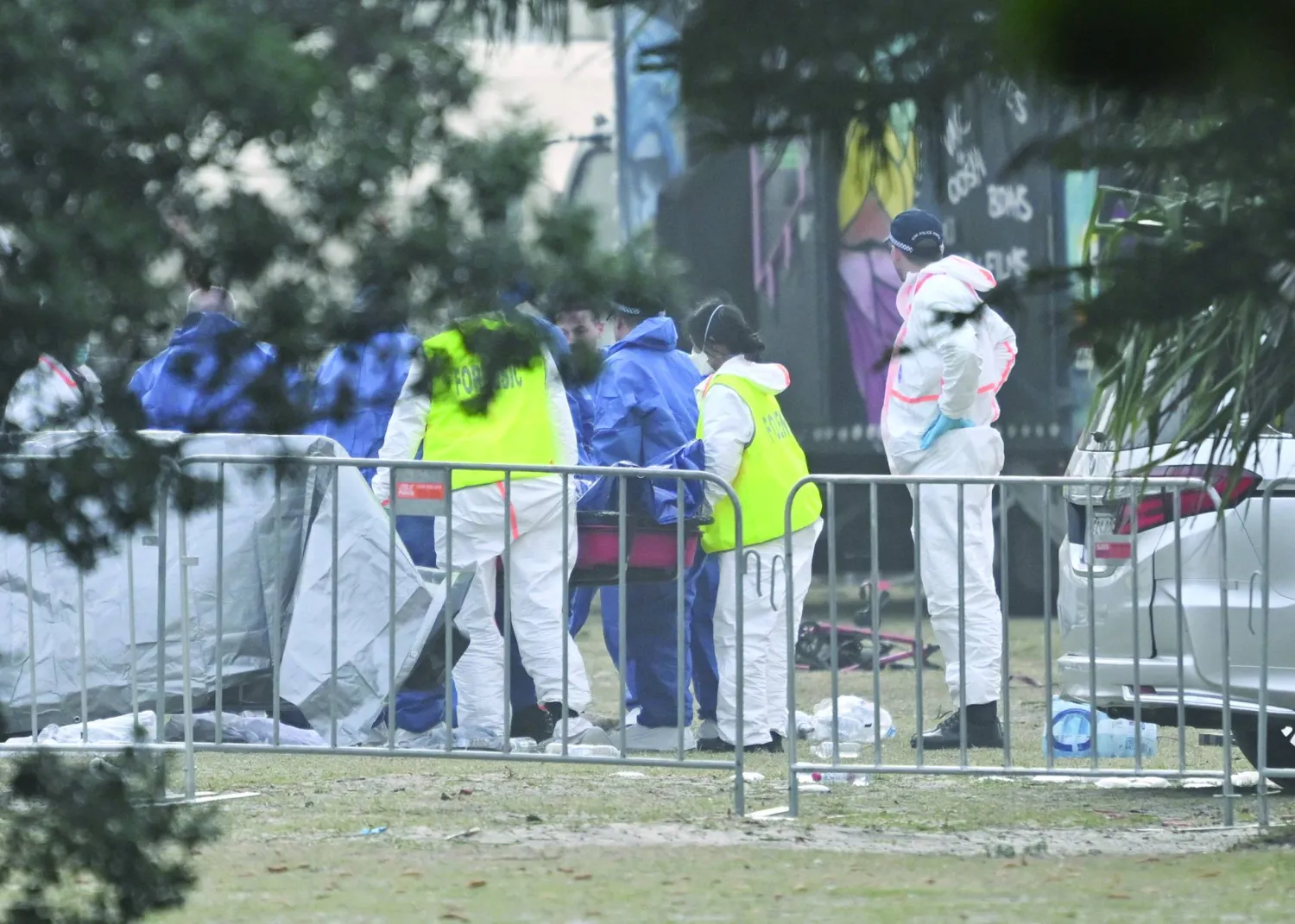 خبراء الأدلة الجنائية خلال معاينة جثة أحد الضحايا بموقع إطلاق النار بشاطئ بونداي في سيدني (أرشيفية - إ.ب.أ)