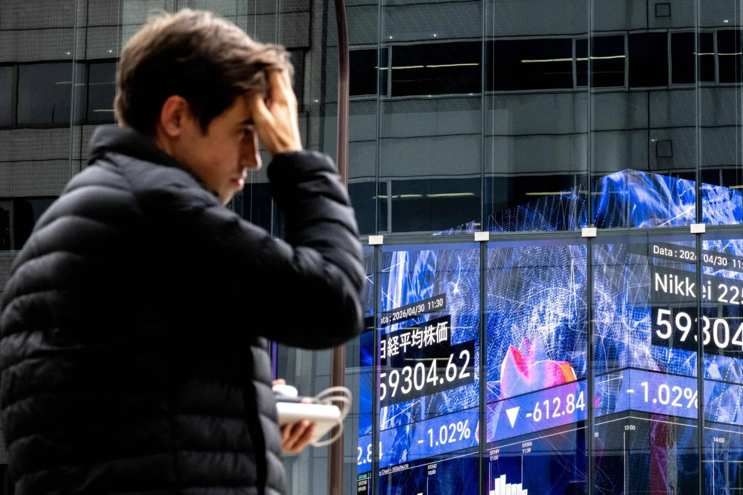 متداول يمر أمام لوحة أسعار إلكترونية في بورصة طوكيو (أ.ف.ب)
