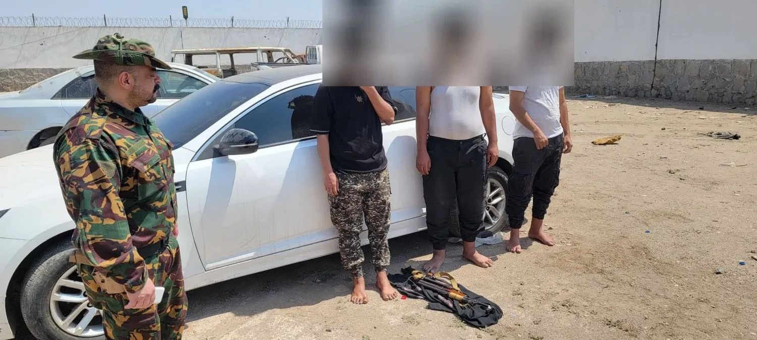 رجل أمن يقف بجوار عدد من أفراد الخلية التي تتهمها أجهزة الأمن اليمنية بالتخطيط لاغتيالات (الحكومة اليمنية)