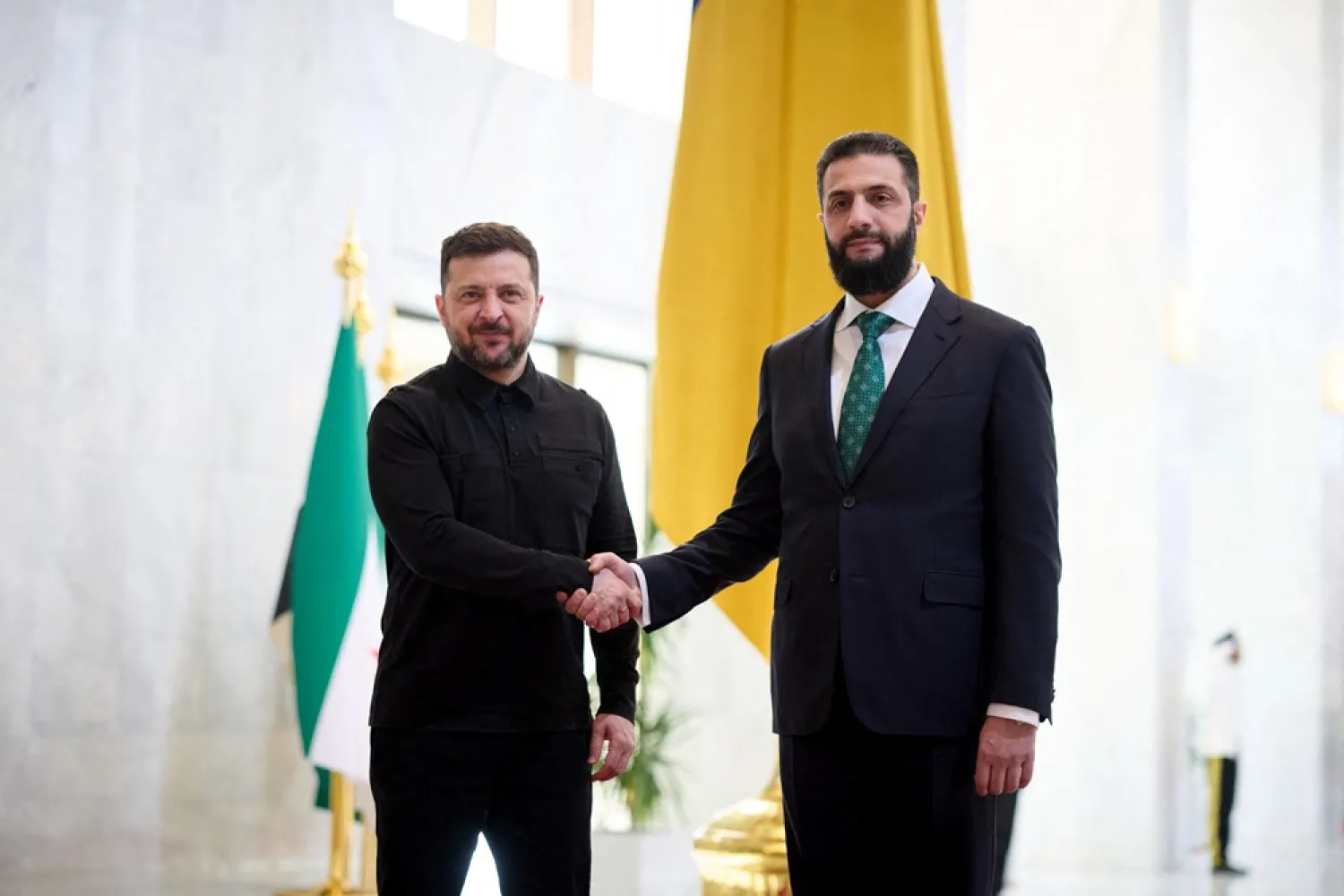 This handout photograph taken and released by the Ukrainian Presidential Press Service on April 5, 2026 shows Ukraine's President Volodymyr Zelenskyy (L) and Syrian President Ahmed al-Sharaa shaking hands during their meeting in Damascus. (Handout / Ukrainian Presidential Press Service / AFP) 