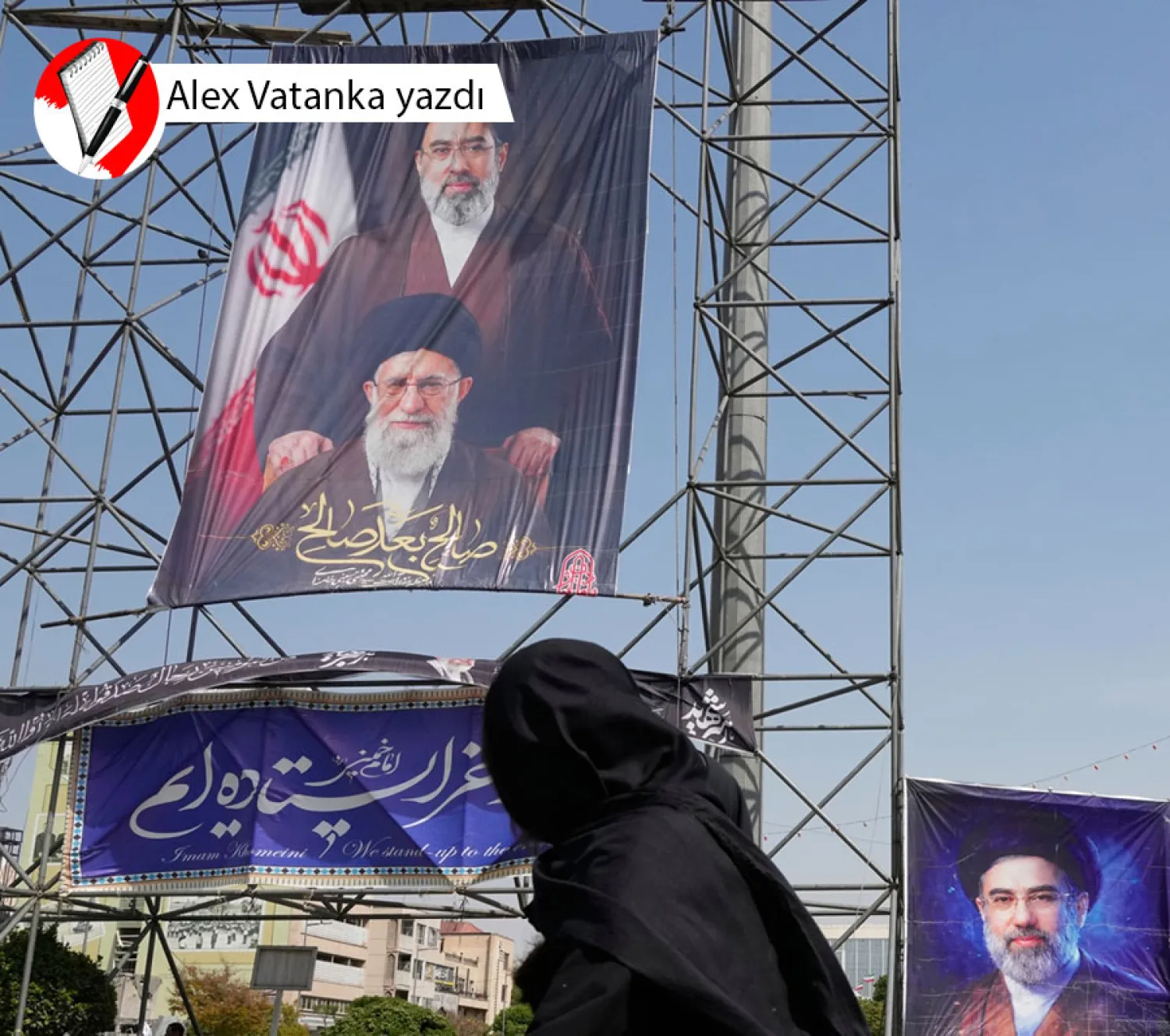 Tahran'da bir kadın, ABD-İsrail saldırılarında öldürülen baba Ali Hamaney ile oğlu Mücteba Hamaney’e ait afişlerin önünden geçiyor (AP)