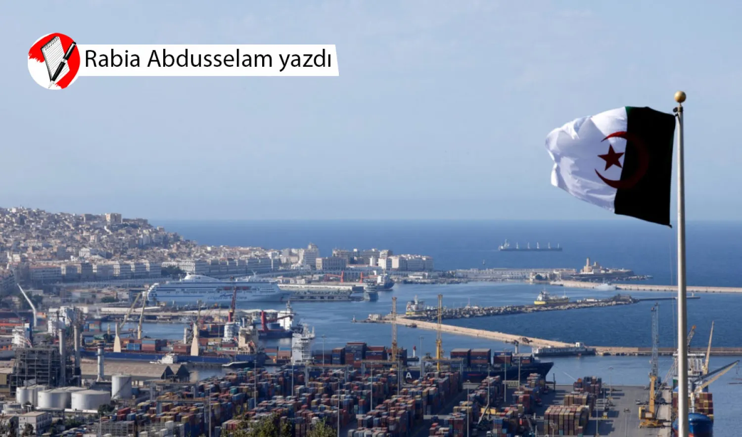 Cezayir Körfezi'nin yakınlarında Cezayir bayrağı dalgalanırken başkentte ‘Kasbah’ olarak bilinen eski şehir (solda) ve nakliye konteynerleri (sağda) görülüyor, 25 Ağustos 2022 (AFP)