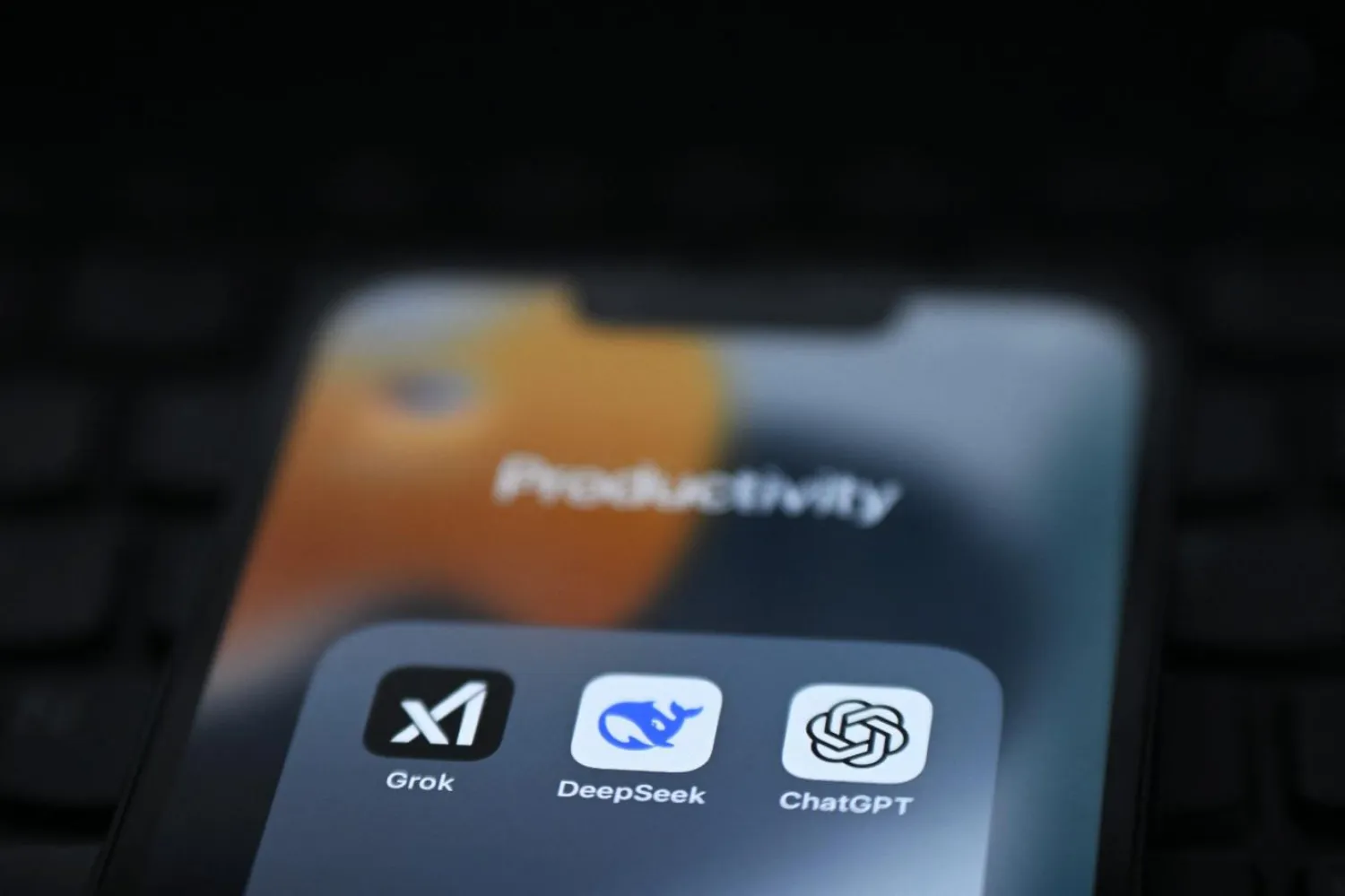 Telefon ekranında gösterilen Grok, DeepSeek ve ChatGPT uygulamaları (AFP)