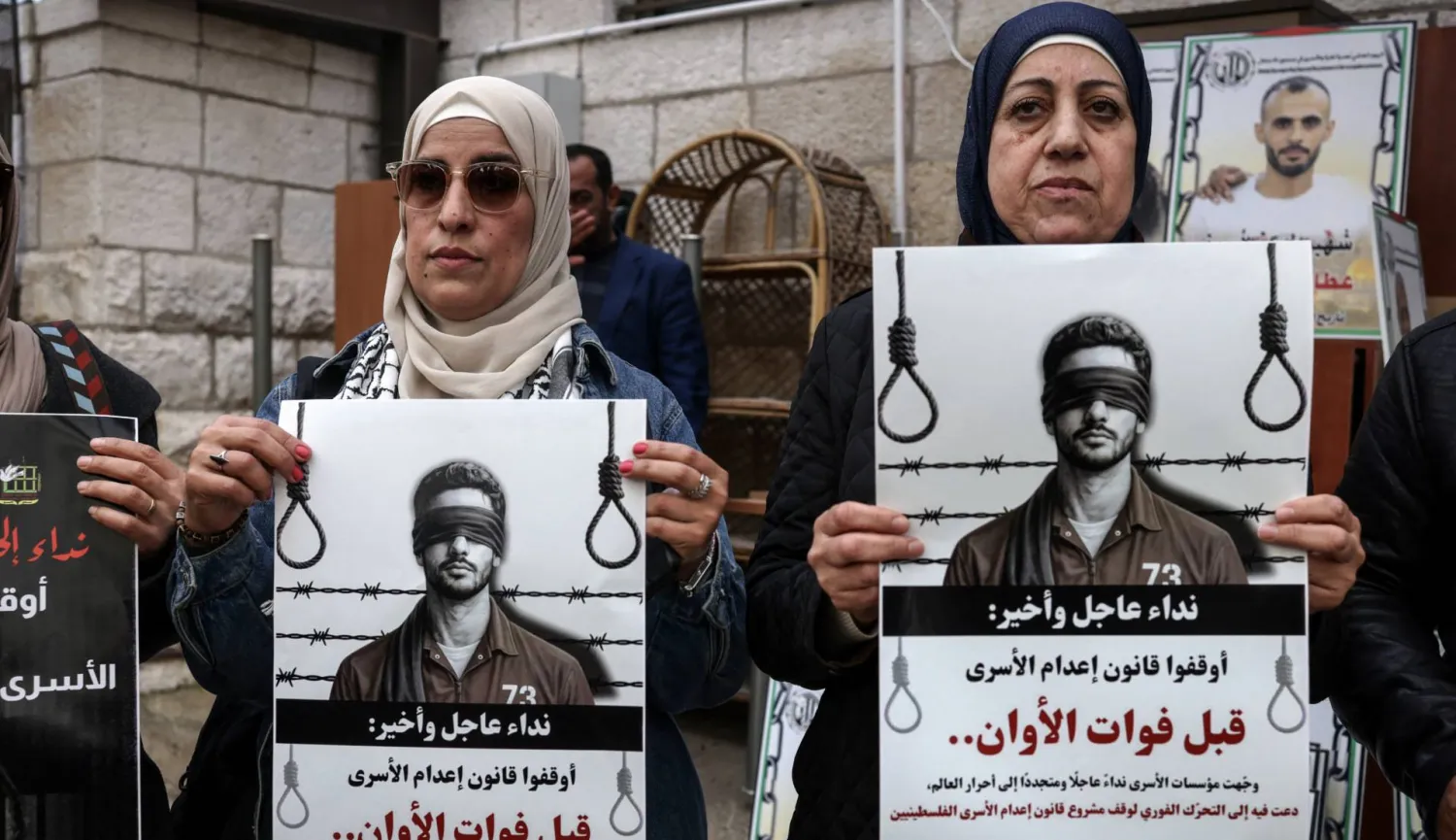 Protesters hold placards outside the Red Cross offices in Ramallah, in the Israeli-occupied West Bank, on March 31, 2026, during a rally against a bill approved by Israel's parliament that would allow the execution of Palestinians convicted on terror charges for deadly attacks. (AFP via Getty Images) 