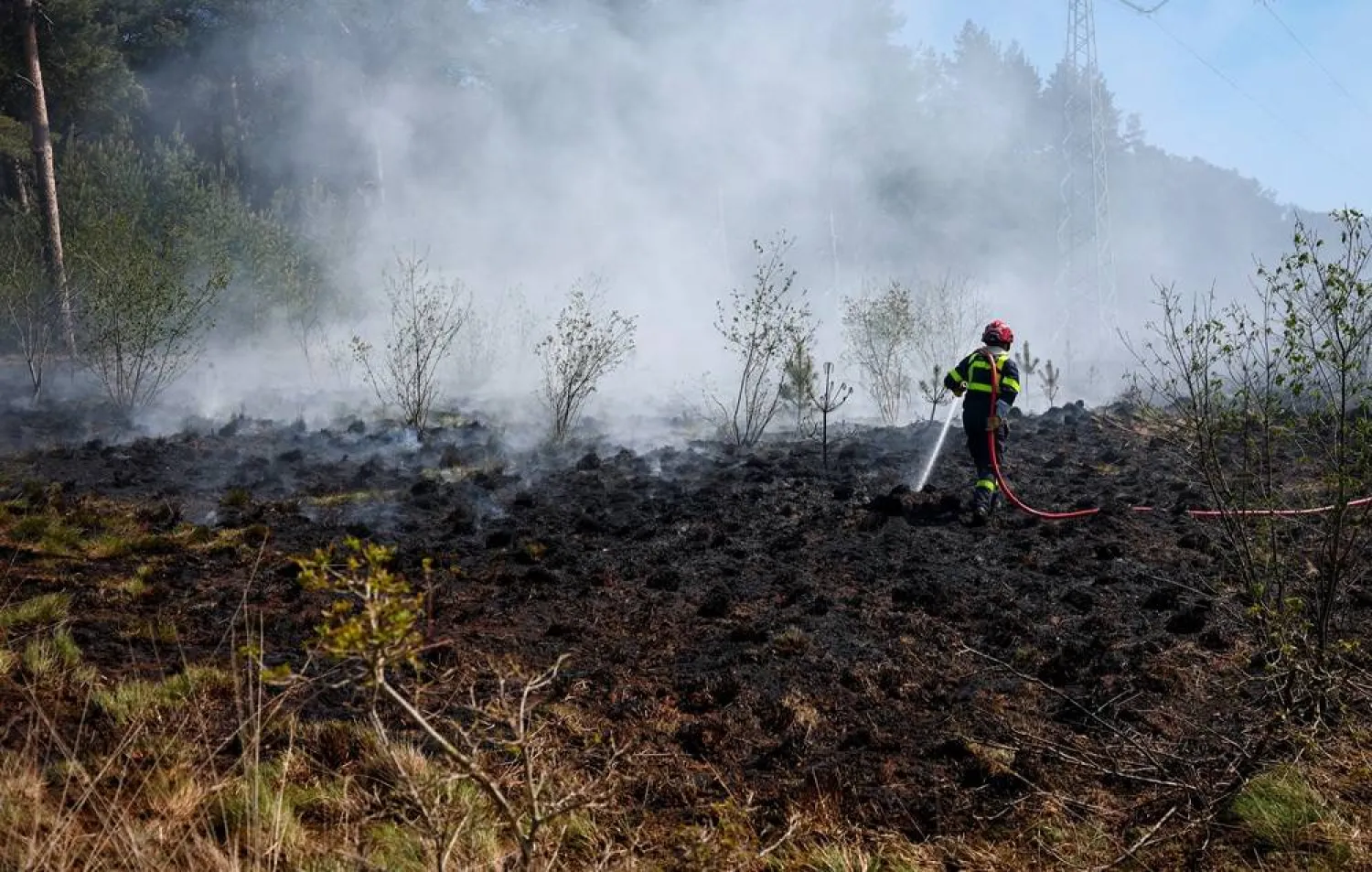 A French firefighter douses burning vegetation during a bushfire in Budel, Netherlands May 1, 2026. (Reuters) 