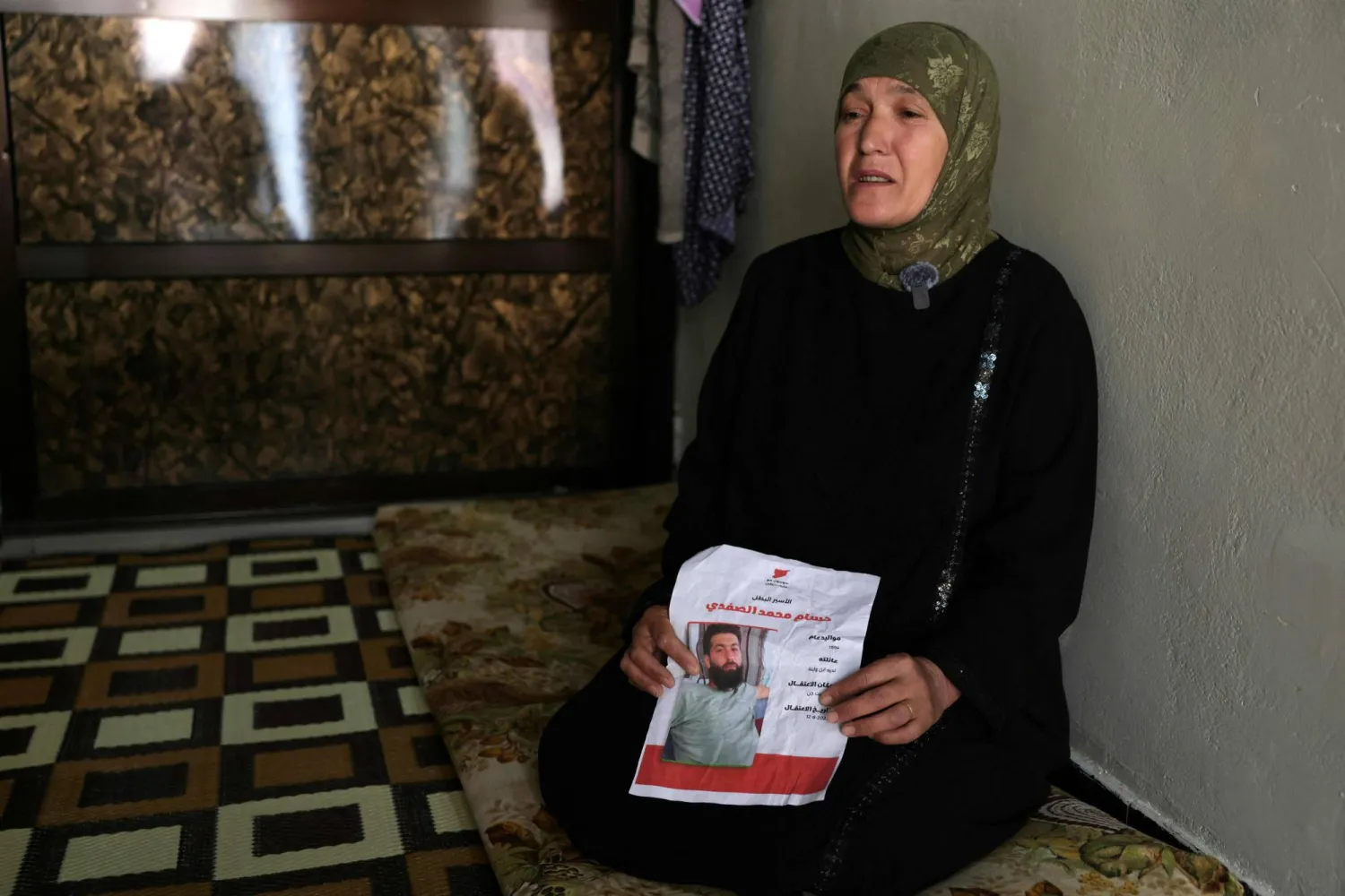 Fifty-three-year-old Syrian Aicha al-Safadi, holds the a picture of her son Hassane Mohammed al-Safadi, with details of when he was detained by Israel as she sits in her house in the southern Syrian village of Beit Jinn, near the Israeli-annexed Syrian Golan Heights and at the foot Mount Hermon, known in Arabic as Jabal al-Sheikh on April 29, 2026. (AFP)