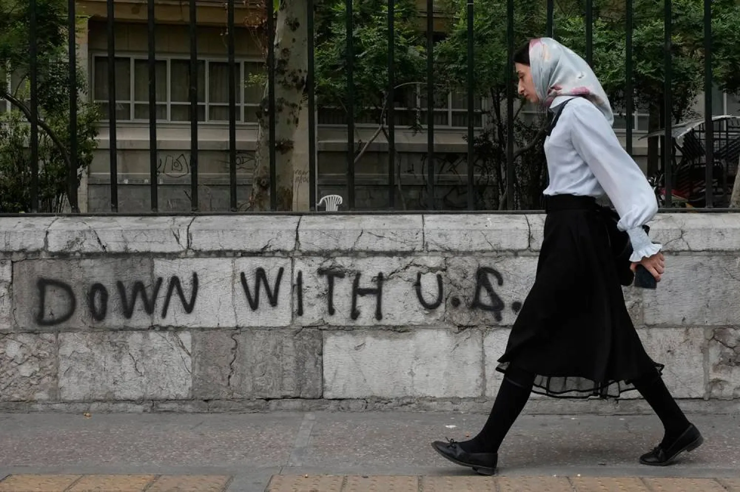 A woman walks past an anti-US graffiti painted on the wall of the Tehran University on Enqelab-e-Eslami street in downtown Tehran, Iran, Saturday, April 25, 2026. (AP)
