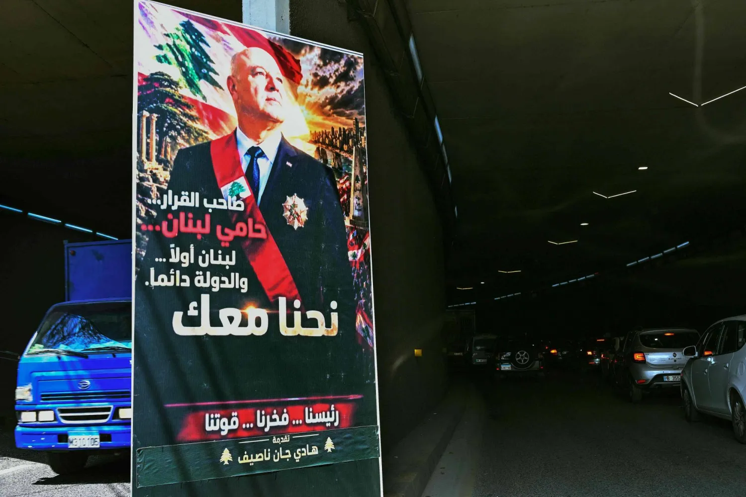 A poster depicting the portrait of Lebanon's President Joseph Aoun that reads "The decision-maker, the protector of Lebanon, Lebanon first...The State always. We are with you" hangs at the entrance of a tunnel on a street in Beirut (Photo by Joseph EID / AFP)