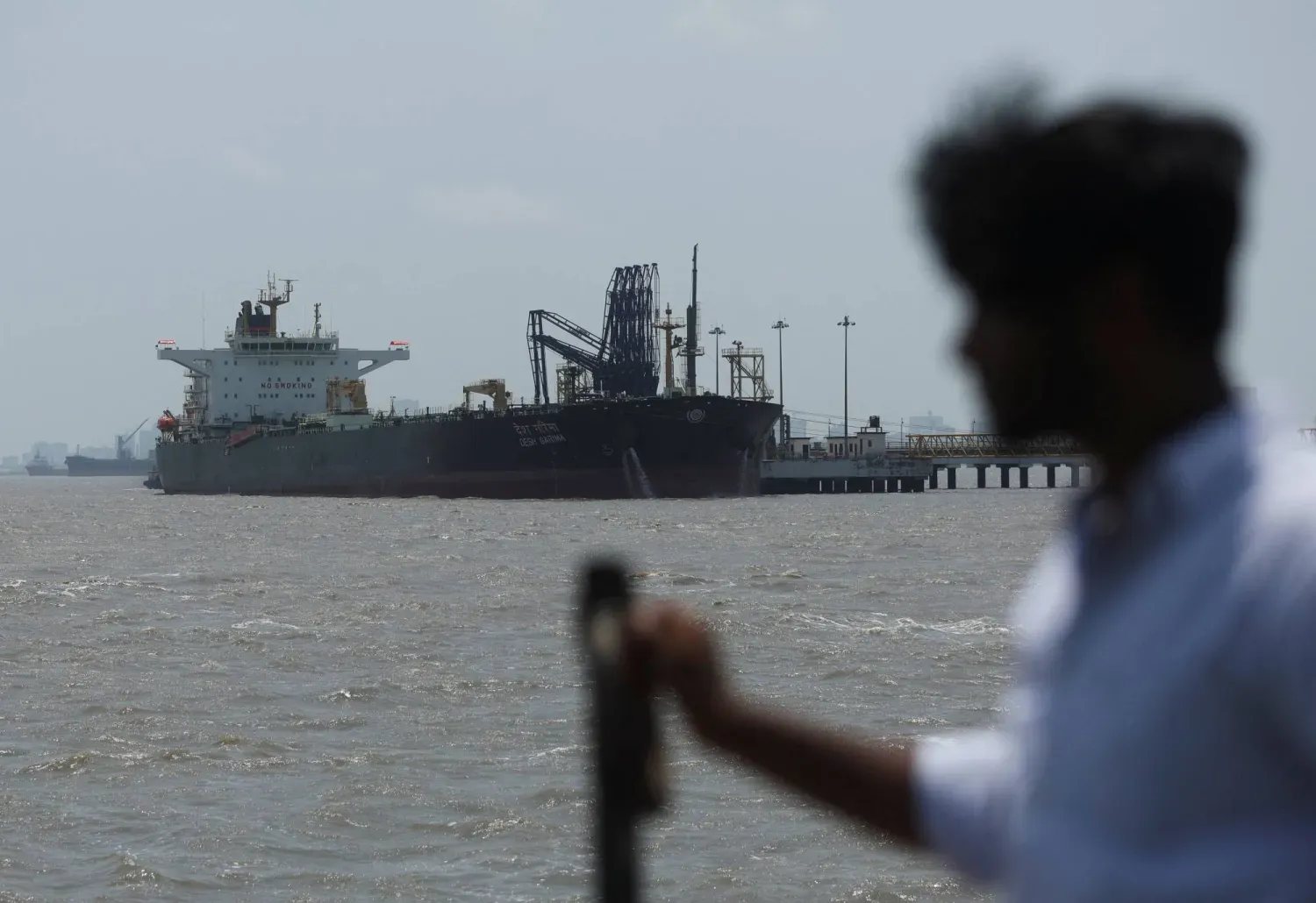 Hürmüz Boğazı'nı geçtikten sonra Mumbai'de petrol yükünü boşaltan "Desh Garima" tankerine bakan bir adam (Arşiv-Reuters)