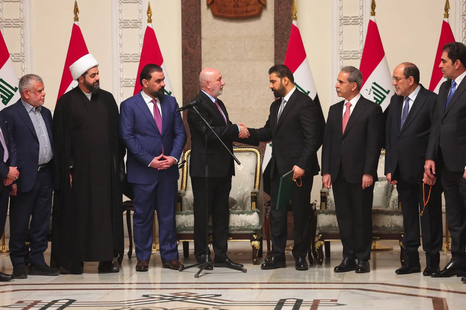 صورة نشرها المكتب الصحافي لرئاسة الجمهورية العراقية يوم 27 أبريل 2026 تظهر الرئيس العراقي نزار آميدي وهو يصافح رئيس الوزراء العراقي الجديد علي الزيدي (أ.ف.ب)