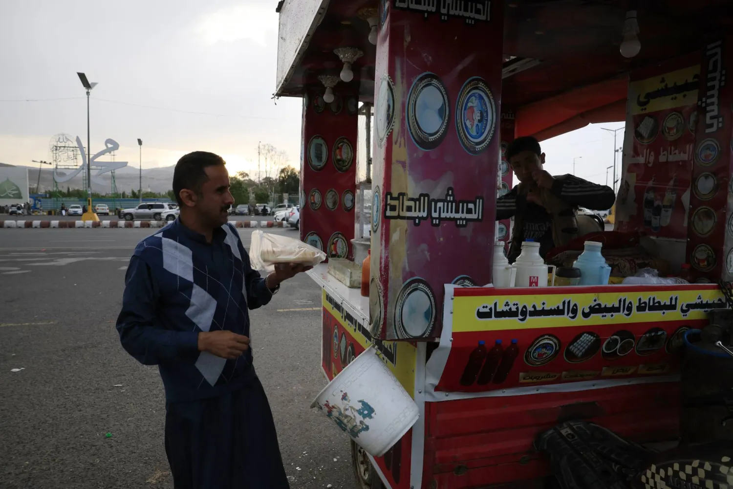 A person (L) buys snacks from a mobile cart in Sanaa, Yemen, 27 April 2026.  EPA/YAHYA ARHAB