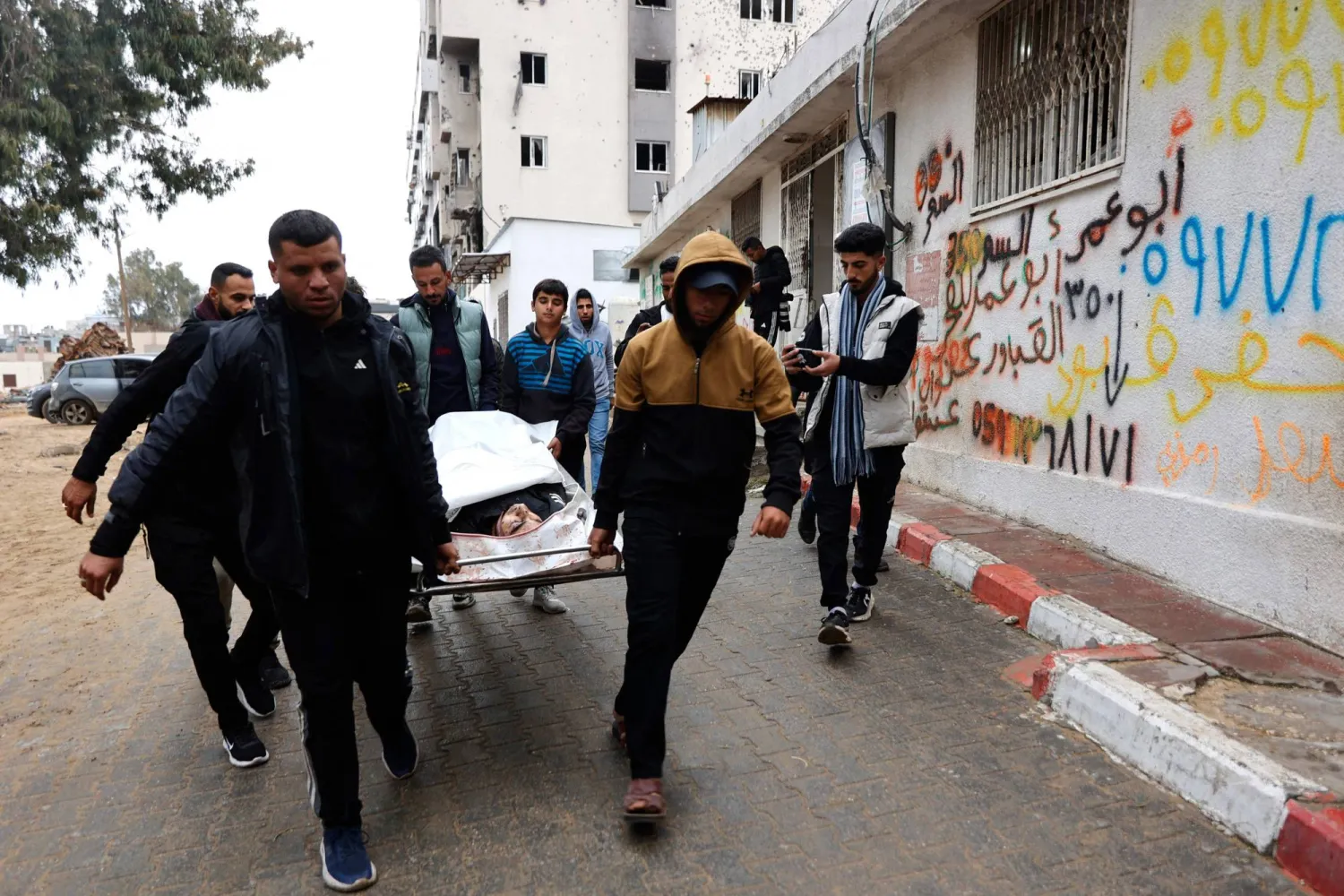 فلسطينيون يحملون قريباً لهم إلى أحد مستشفيات قطاع غزة (أ.ف.ب)