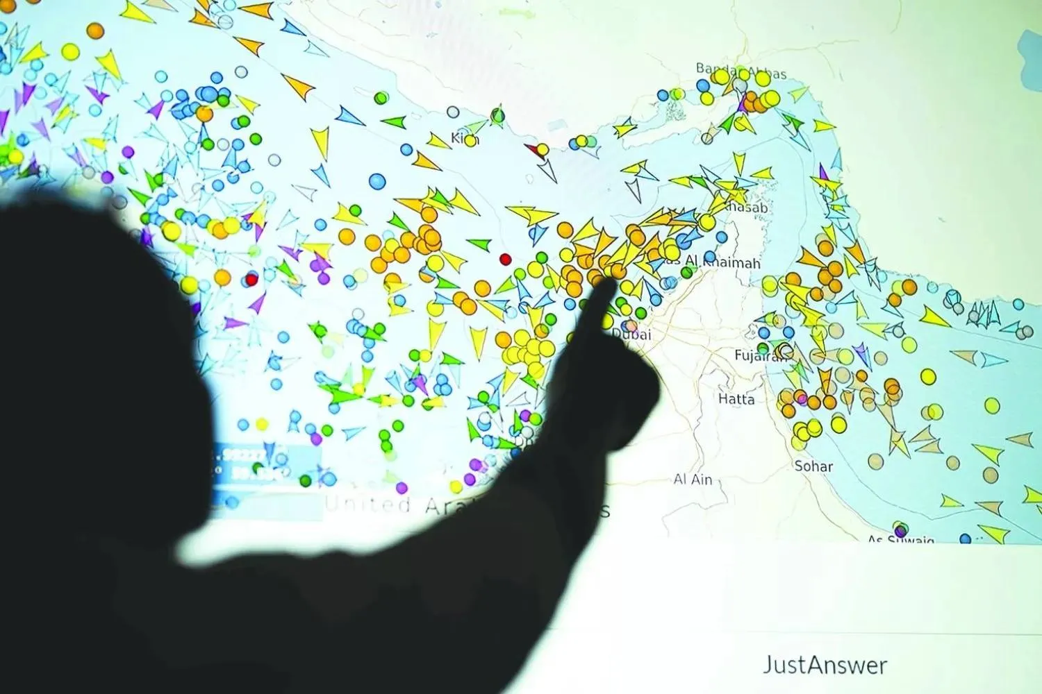 A photo illustration taken in Nicosia on May 4, 2026, shows a person in front of a large screen displaying vessel movements in the Strait of Hormuz on a ship-tracking website. (AFP) 