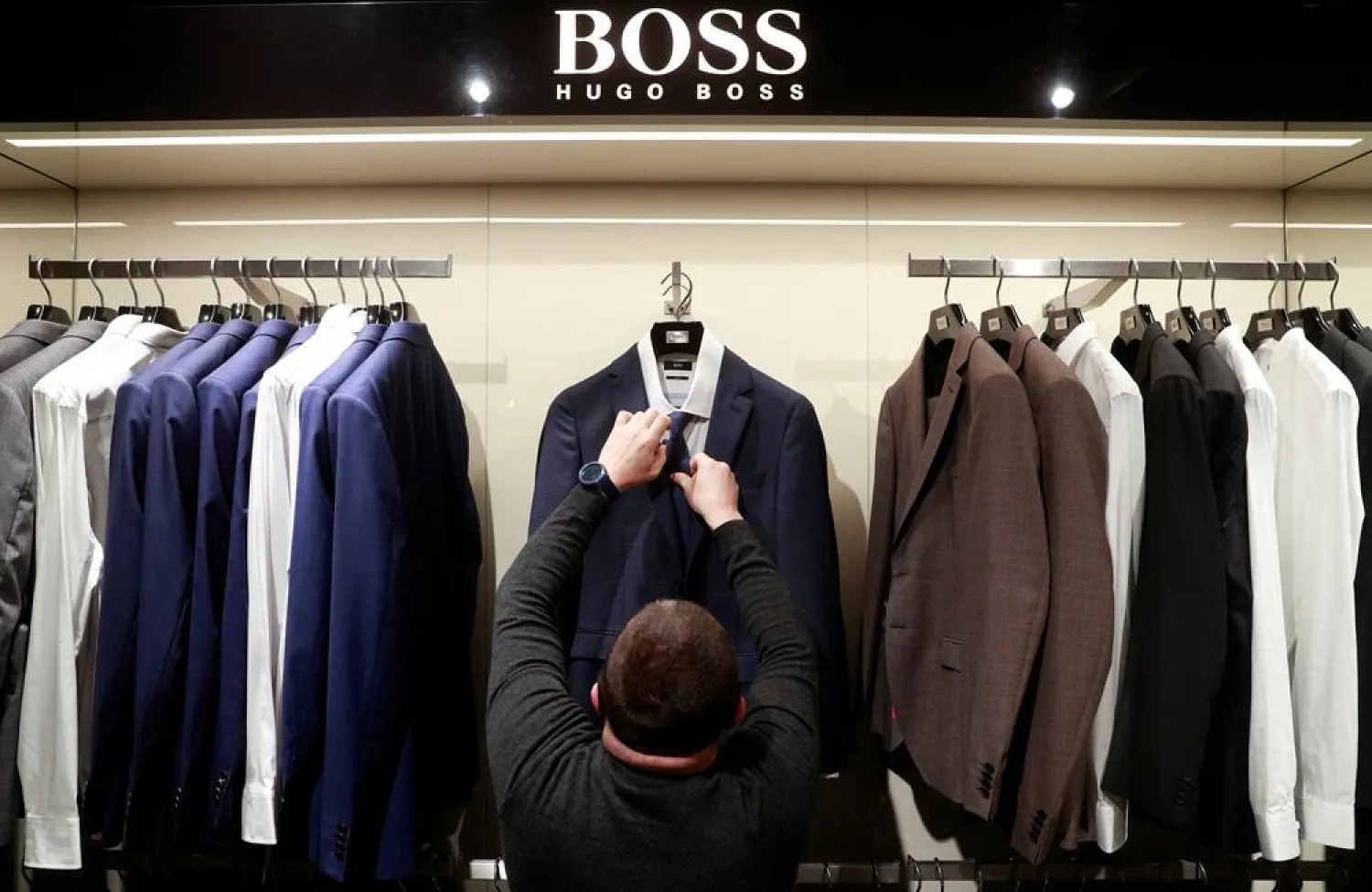 An employee displays suits at the Hugo Boss section of the Central Universal Department Store (TsUM), in Kyiv, Ukraine January 25, 2021. (Reuters)