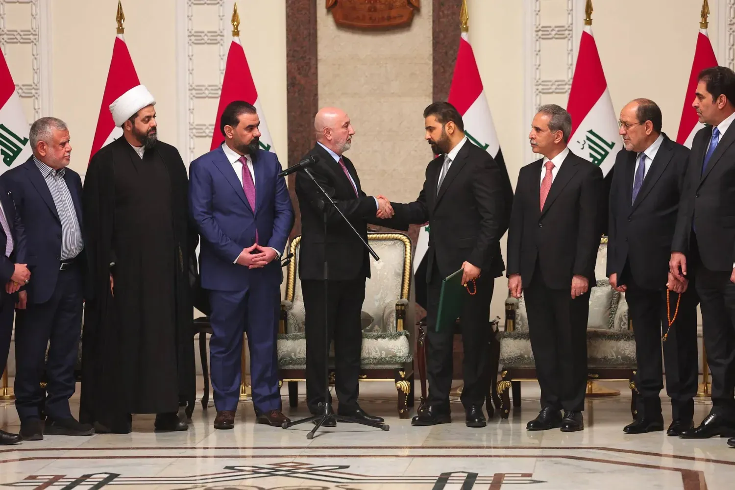 Irak Cumhurbaşkanı Nizar Amidi, hükümeti kurmakla görevlendirilen Ali ez-Zeydi ile tokalaşırken, 27 Nisan 2026 (Irak Cumhurbaşkanlığı Basın Ofisi/AFP)