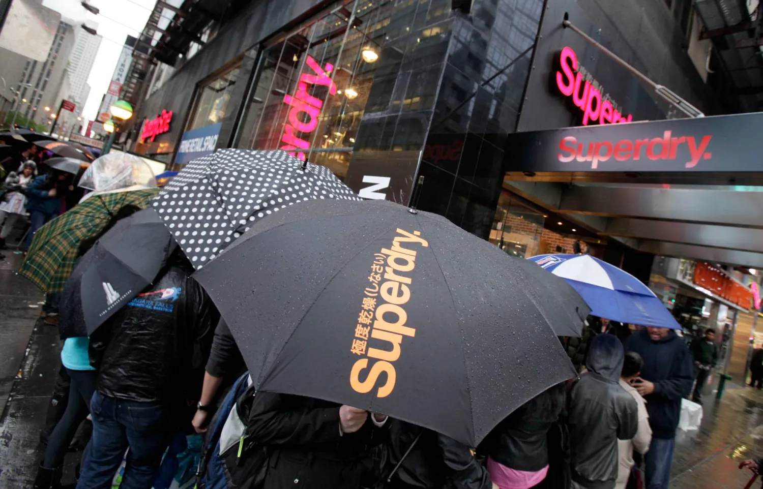 FILE - People cue in the rain waiting for the grand opening of the Superdry store in New York's Times Square, on May 9, 2012. (AP Photo/Richard Drew, File)