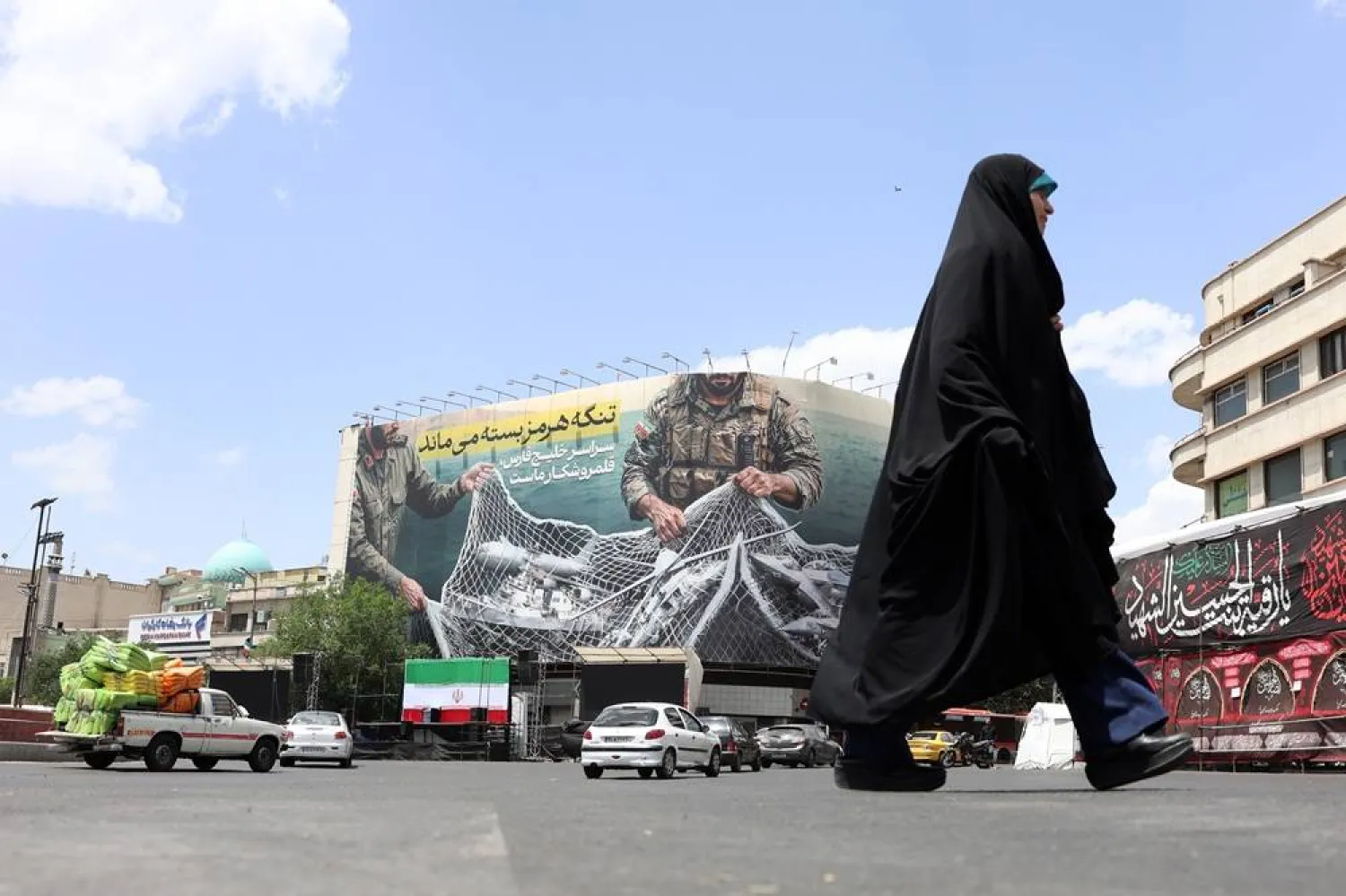 An Iranian woman walks next to a huge anti-US billboard carrying a sentence reading in Persian “The Strait of Hormuz remains closed” at the Engelab (Revolution) square in Tehran, Iran, 08 May 2026. (EPA)