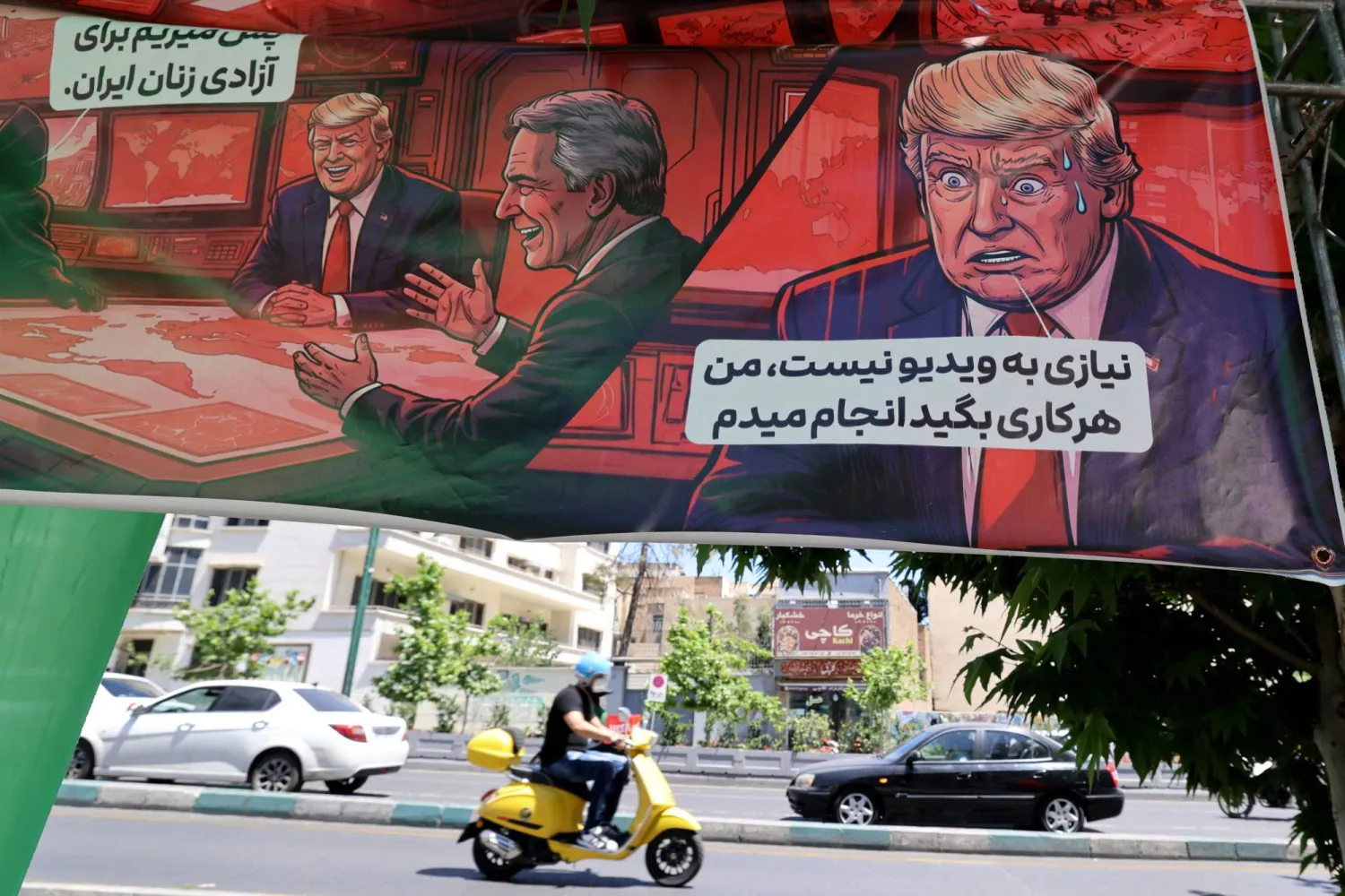إيراني يقود دراجة نارية أمام لافتة تعرض رسماً للرئيس الأميركي وتضم عبارتين: «إذن نحن ذاهبون من أجل حرية النساء الإيرانيات» (يسار) و«لا حاجة إلى فيديو.. سأفعل كل ما تقول» (يمين) في طهران يوم 9 مايو 2026 (أ.ف.ب)