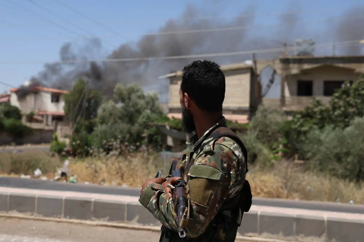 A member of Syria's security forces stands under a sign in the predominantly Druze city of Sweida on July 15, 2025. (AFP)