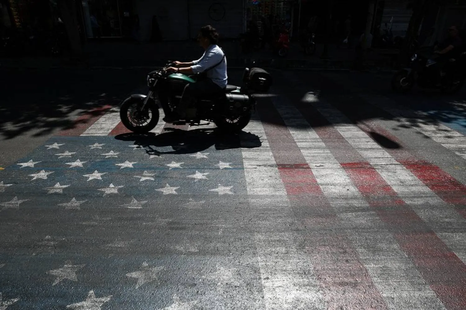 A person rides a motorcycle over a US flag painted on a street, in Tehran, Iran, May 12, 2026. Majid Asgaripour/WANA (West Asia News Agency) via Reuters