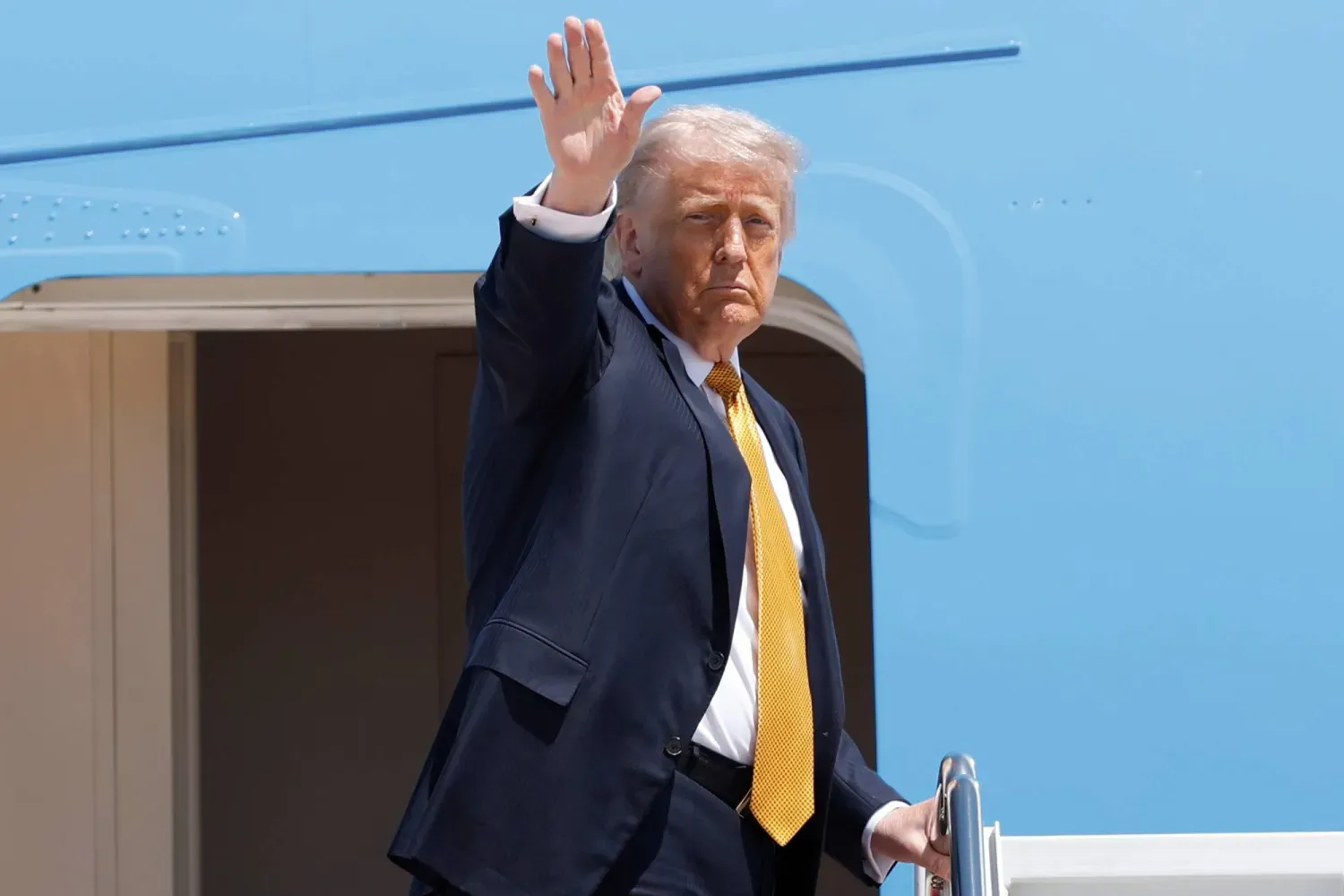 Trump, Maryland'deki Joint Base Andrews'e indikten sonra Air Force One'ın merdivenlerinden el sallıyor (AP)