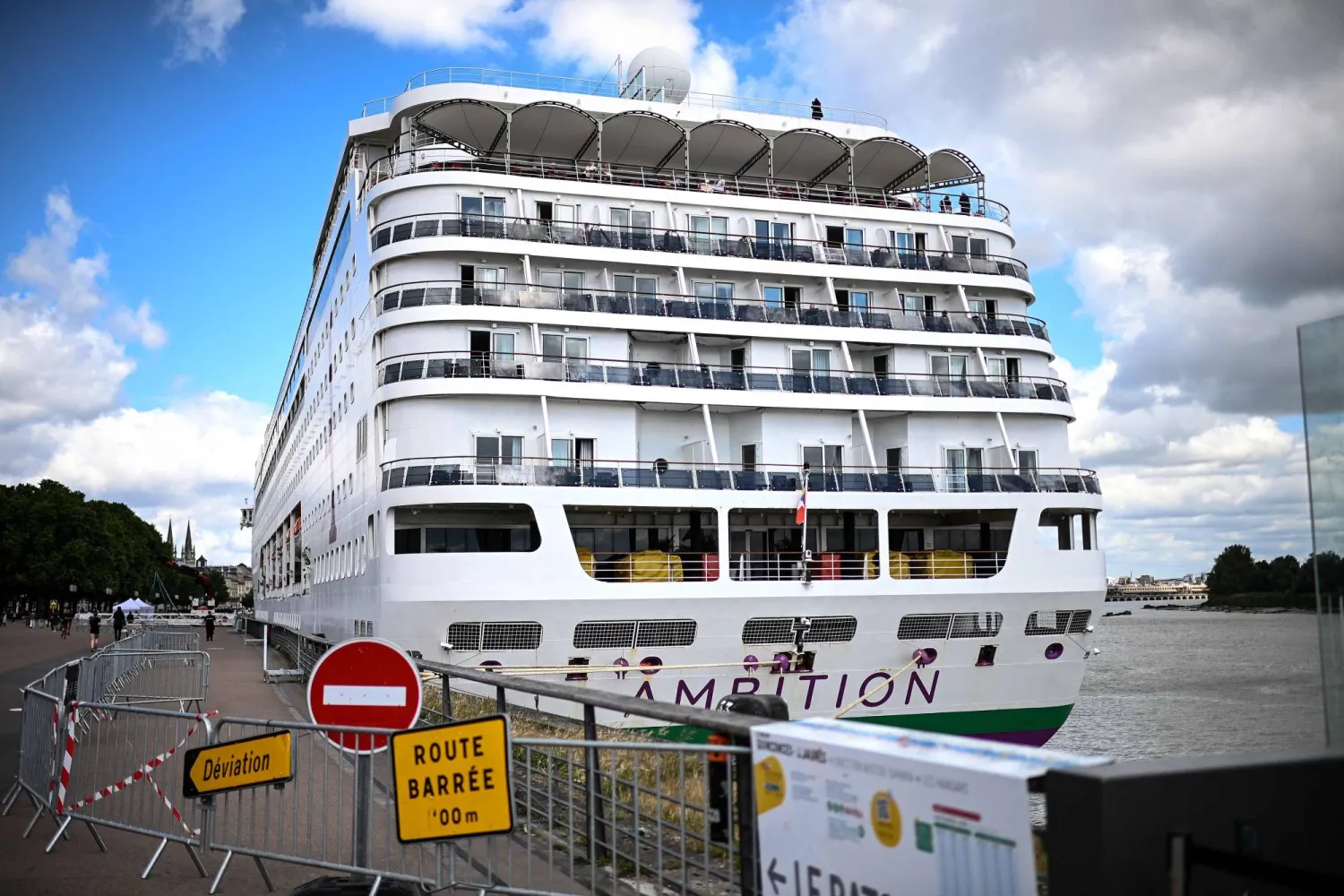Passengers stand aboard the Bahamas-registered cruise ship Ambition after they were confined following the outbreak of a gastrointestinal illness onboard, at the Bordeaux port in Bordeaux, southwestern France on May 13, 2026. (AFP)