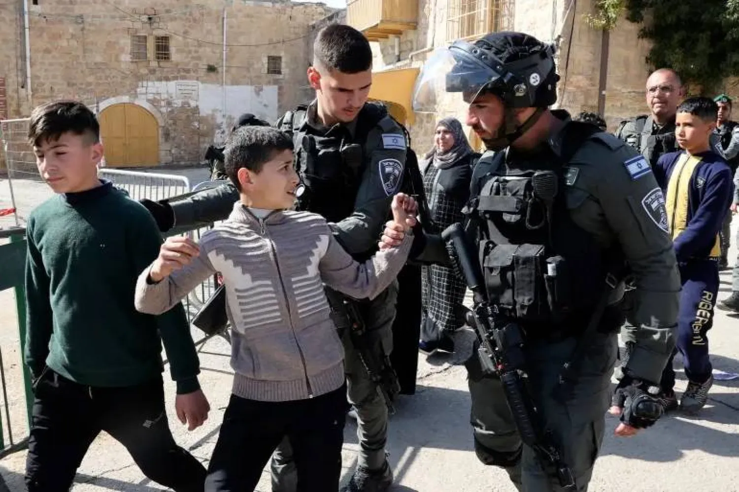 عناصر من الشرطة الإسرائيلية يعتقلون أطفالاً فلسطينيين في الخليل بالضفة الغربية (أ.ف.ب)