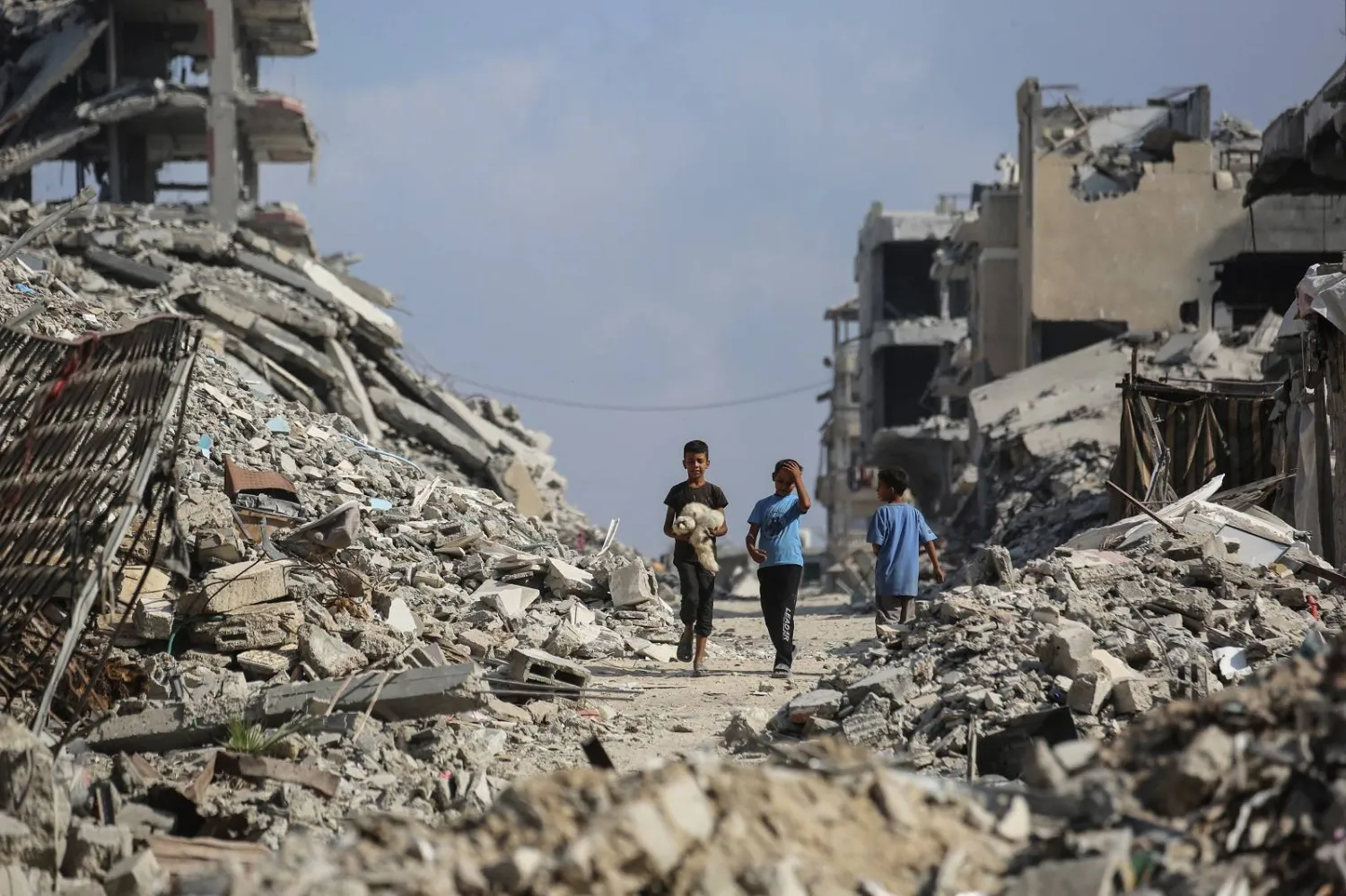أطفال فلسطينيون يشقون طريقهم بين أنقاض المباني في مخيم الشاطئ للاجئين شرق غزة (أ.ف.ب)