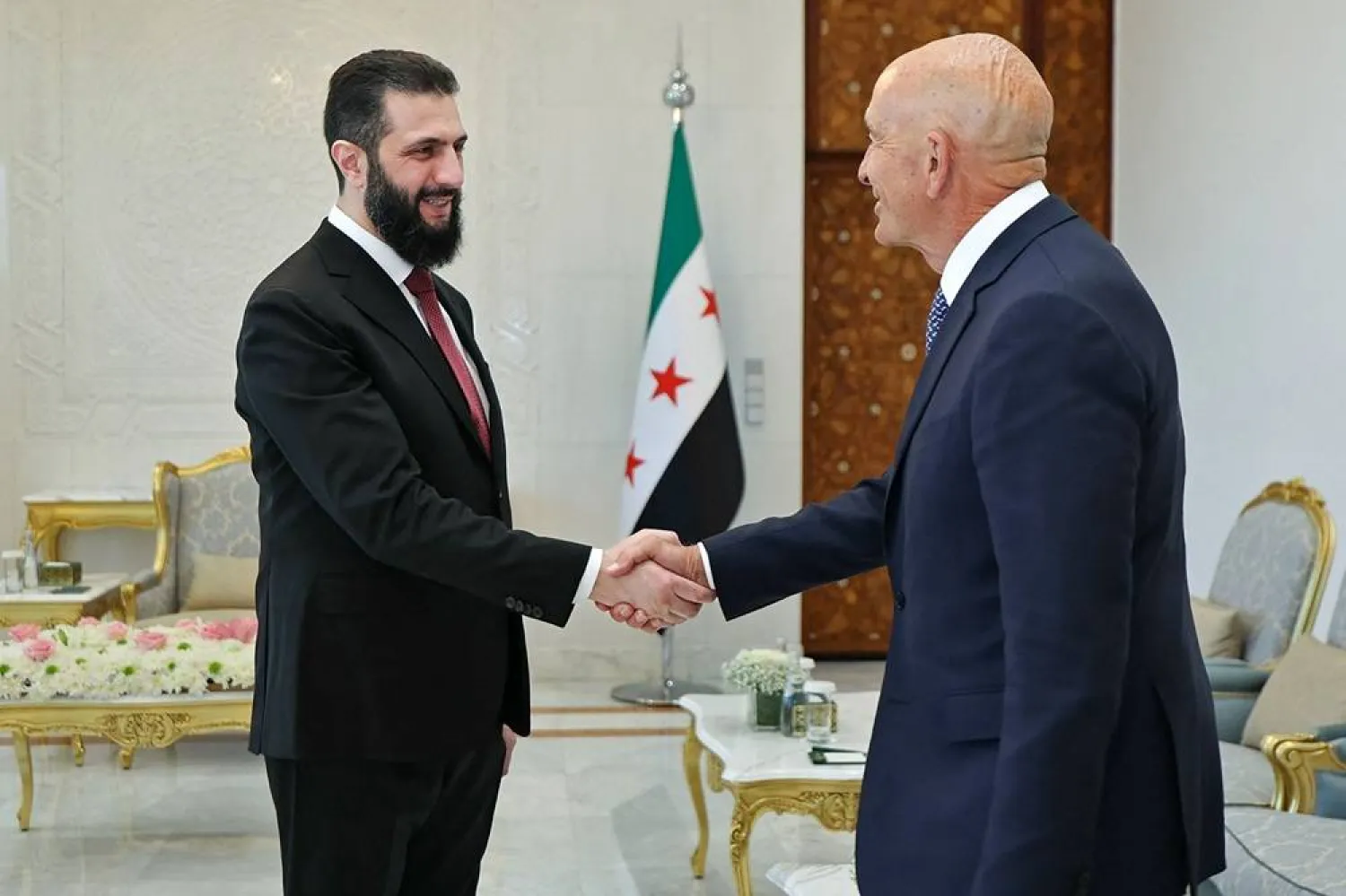 This handout photograph released by the Syrian Arab News Agency (SANA) on May 16, 2026 shows Syria's President Ahmed al-Sharaa (L) shaking hands with US Ambassador to Türkiye and Special Envoy for Syria Tom Barrack before their meeting at the People's Palace in Damascus. (SANA / AFP)  