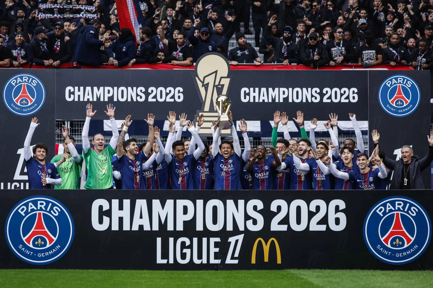  PSG players and Paris Saint-Germain's Spanish head coach Luis Enrique (R) celebrate with the French Ligue 1 trophy after winning the championship ahead of the French L1 football match between Paris FC and Paris Saint-Germain (PSG) at the Stade Jean-Bouin in Paris on May 17, 2026. (AFP) 