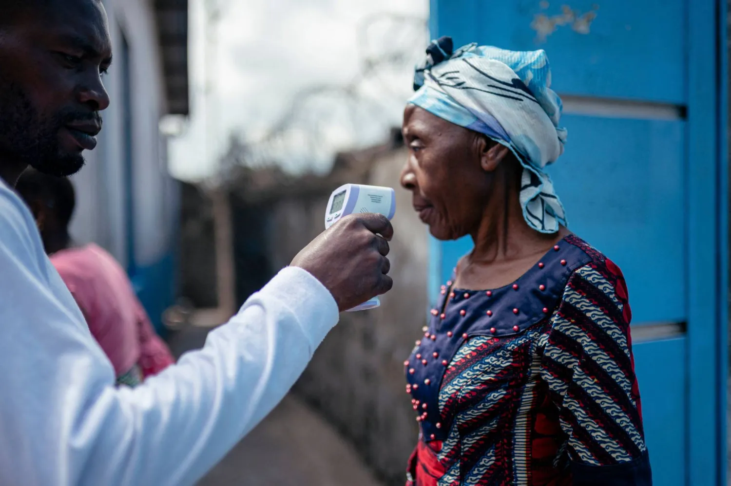 TOPSHOT - A staff member of the CBCA Virunga Hospital checks a visitor痴 temperature using a a contactless infrared thermometer, before allowing her access to the hospital in Goma on May 17, 2026. (Photo by Jospin Mwisha / AFP)