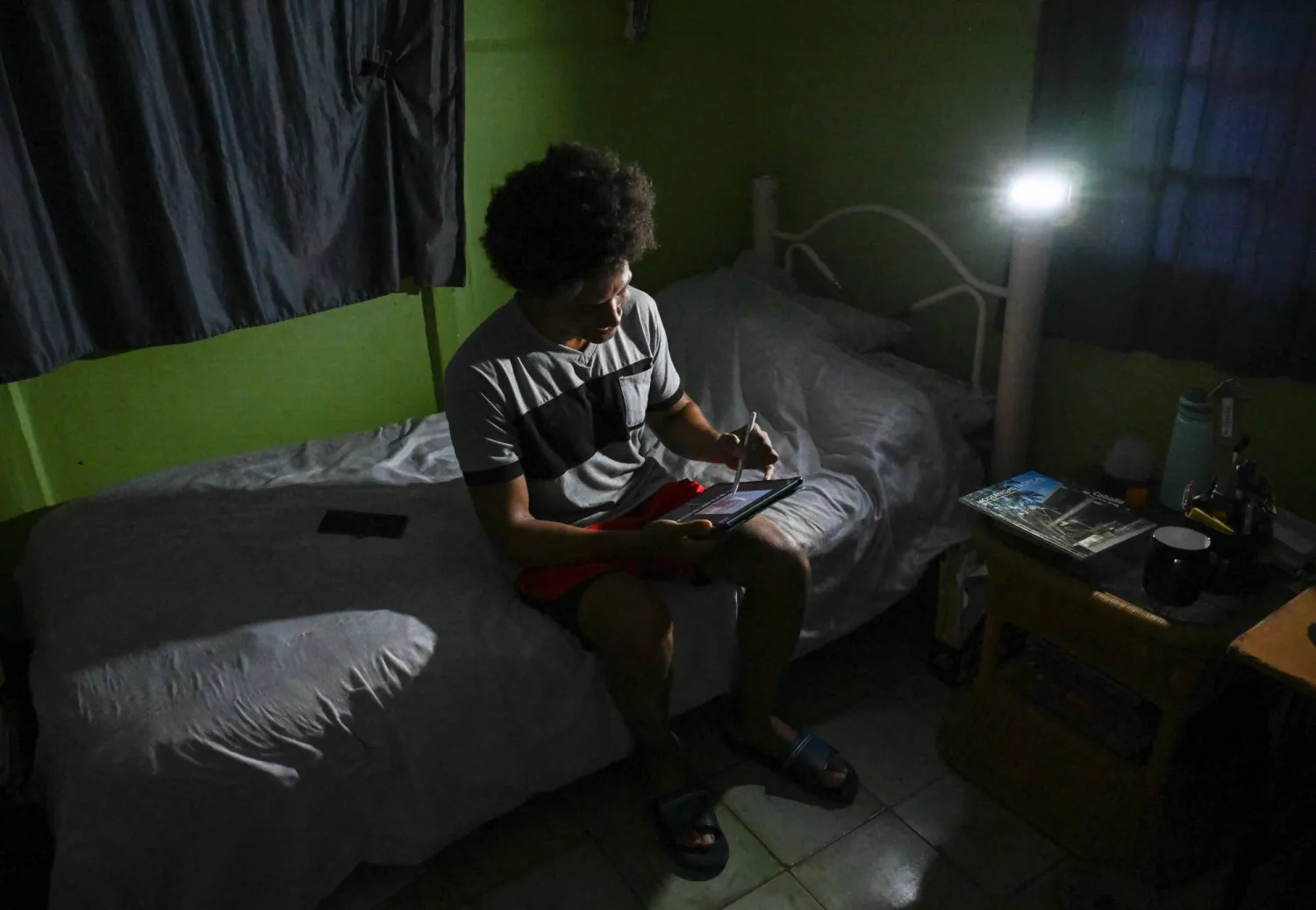 Alfredo Rodriguez, industrial designer and ISDI professor, studies during a power cut in Punta Brava, Havana on May 11, 2026. (AFP)