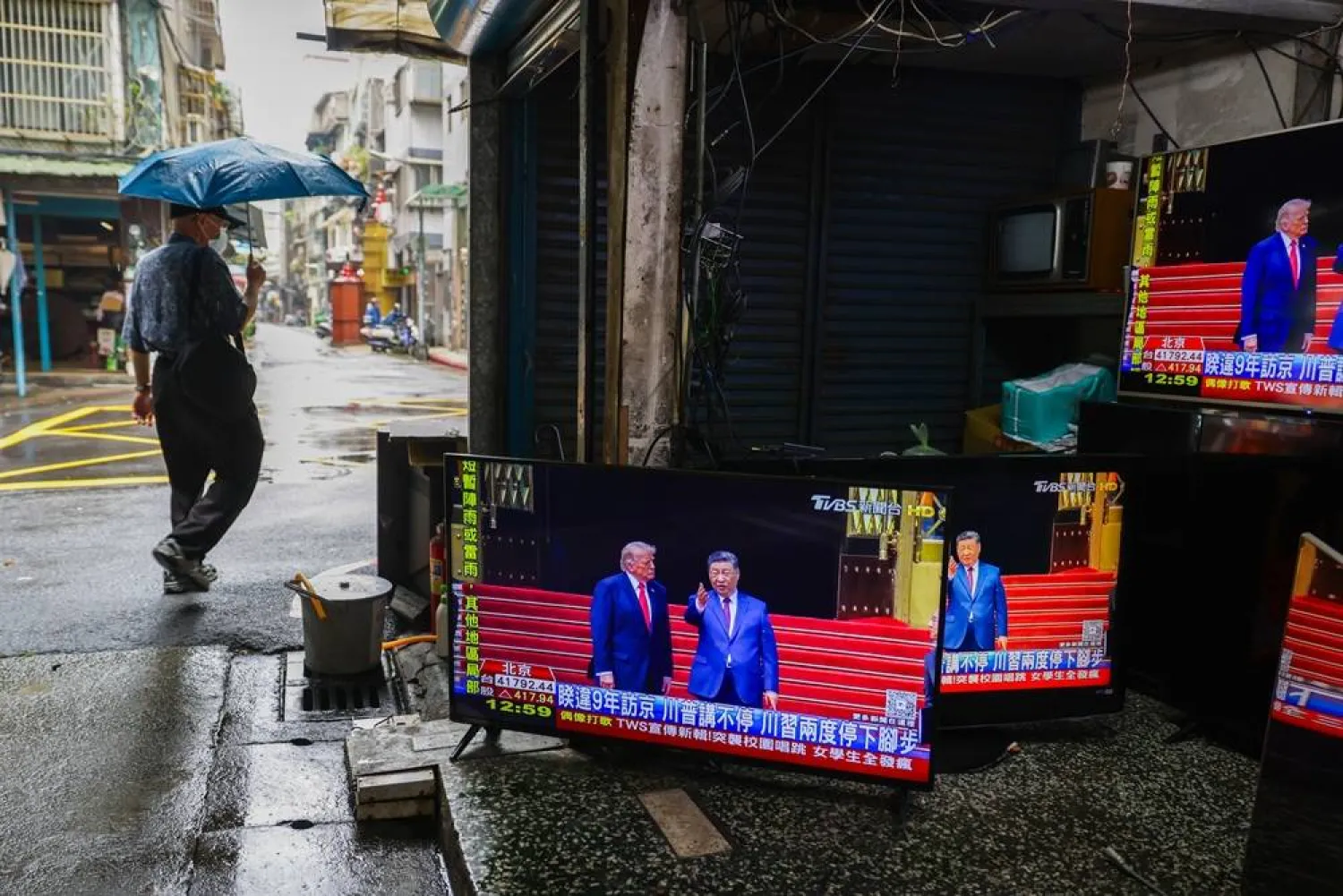 A pedestrian walks past a secondhand and TV repair store, with TV screens broadcasting the Beijing meeting between US President Donald Trump and Chinese President Xi Jinping, in Taipei, Taiwan, 14 May 2026. (EPA)