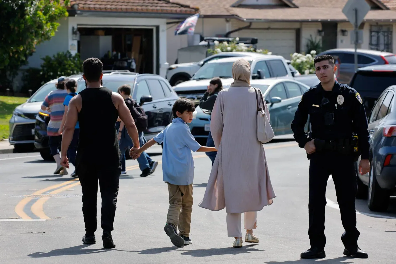 Kaliforniya’daki San Diego İslam Merkezi’nde meydana gelen silahlı saldırının ardından bir çocuk, camiden ayrılırken anne ve babasının ellerini tutuyor (Reuters)