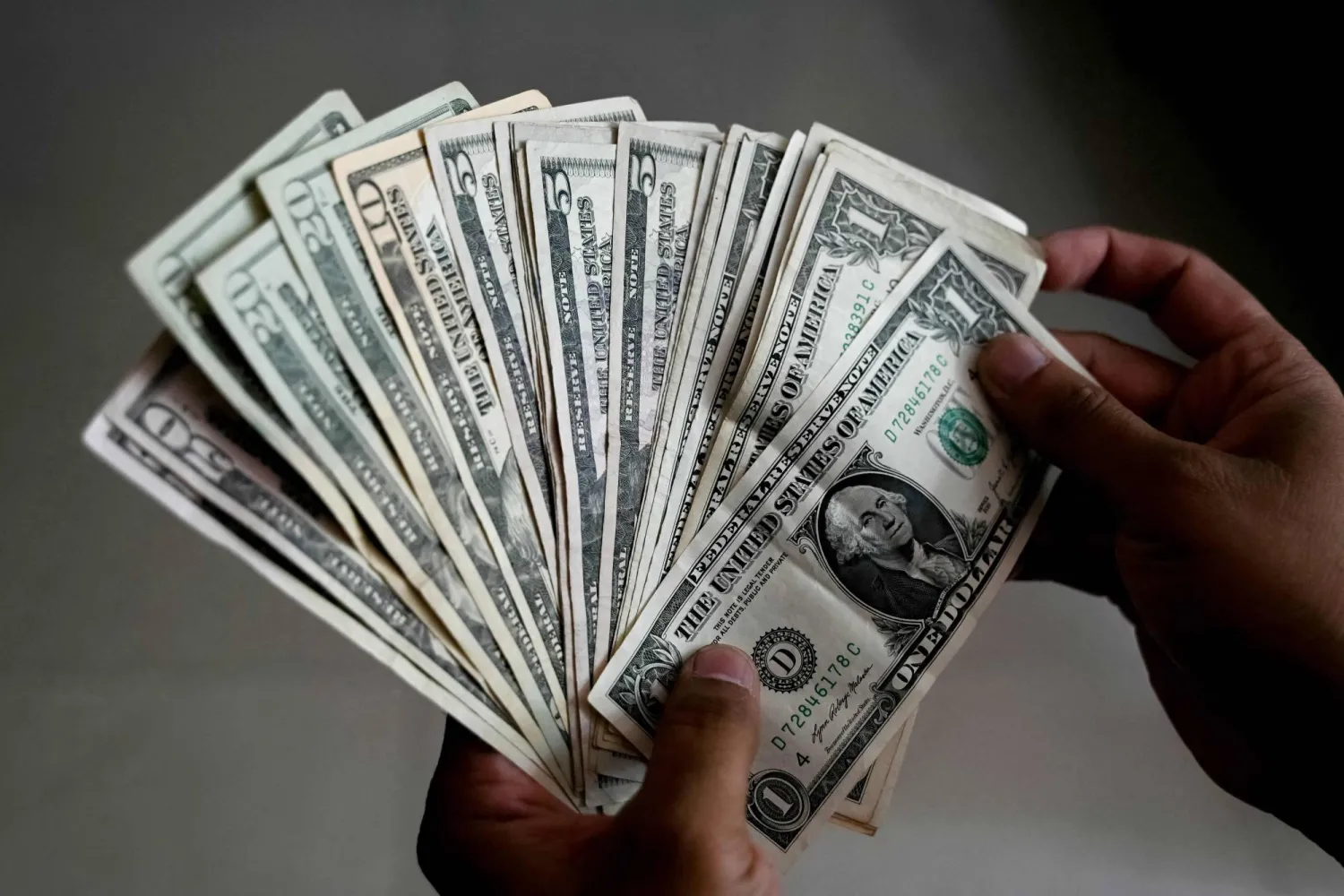  A man counts US dollar currency notes at a foreign exchange office in Hyderabad on May 16, 2026. (AFP) 