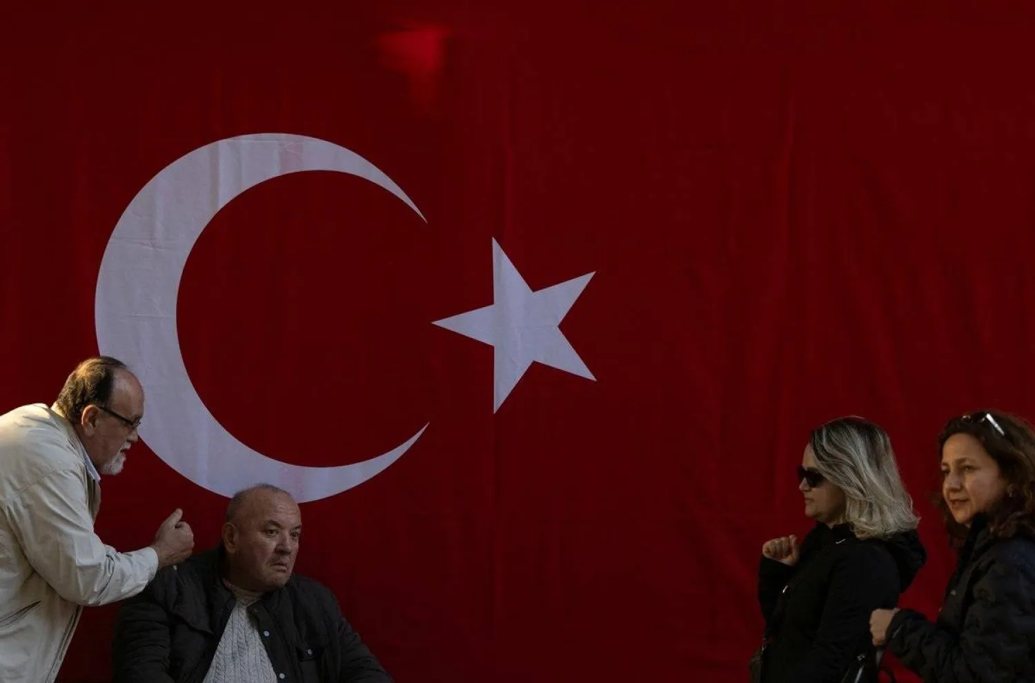 People are seen in front of a Turkish national flag hanged on a wall to mark the 101th anniversary of the Turkish Republic’s foundation a head of the Republic Day, in Istanbul, Türkiye, October 28, 2024. (Reuters) 