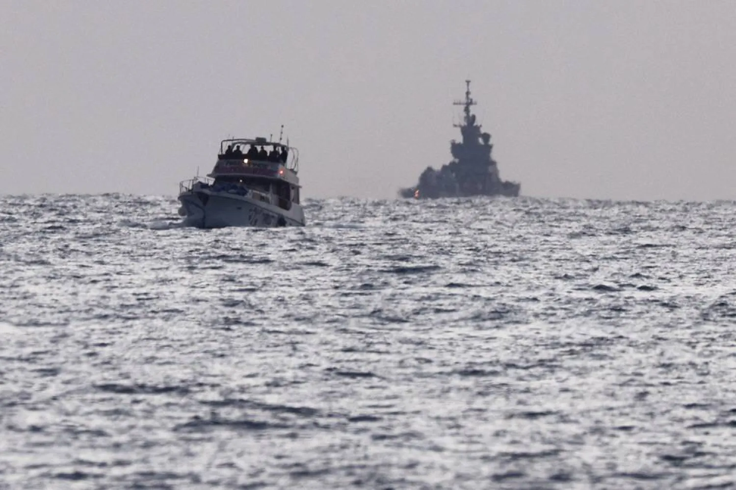  Israeli soldiers are seen on a vessel bearing symbols of the Global Sumud Flotilla, with an Israeli military ship behind it, as seen from Ashdod, southern Israel, May 19, 2026. (Reuters)