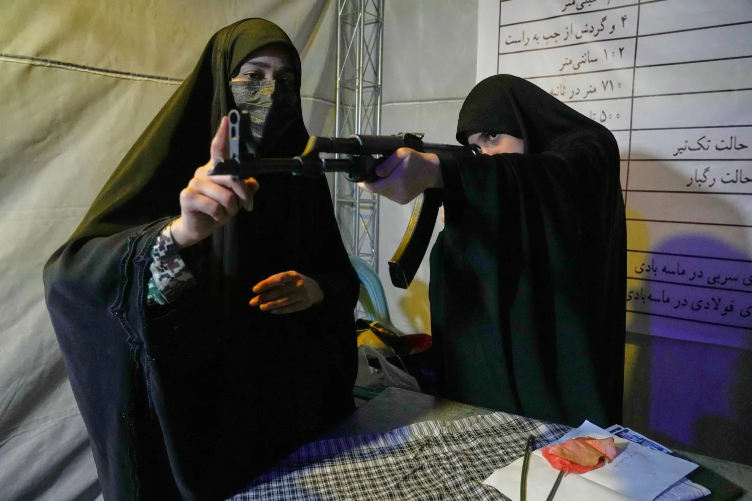متطوعة في قوة «الباسيج» التابعة لـ«الحرس الثوري» (على اليسار) تقدّم تعليمات حول كيفية التعامل مع بندقية كلاشينكوف خلال تدريب على استخدام الأسلحة في طهران يوم 19 مايو 2026 (أ.ب)