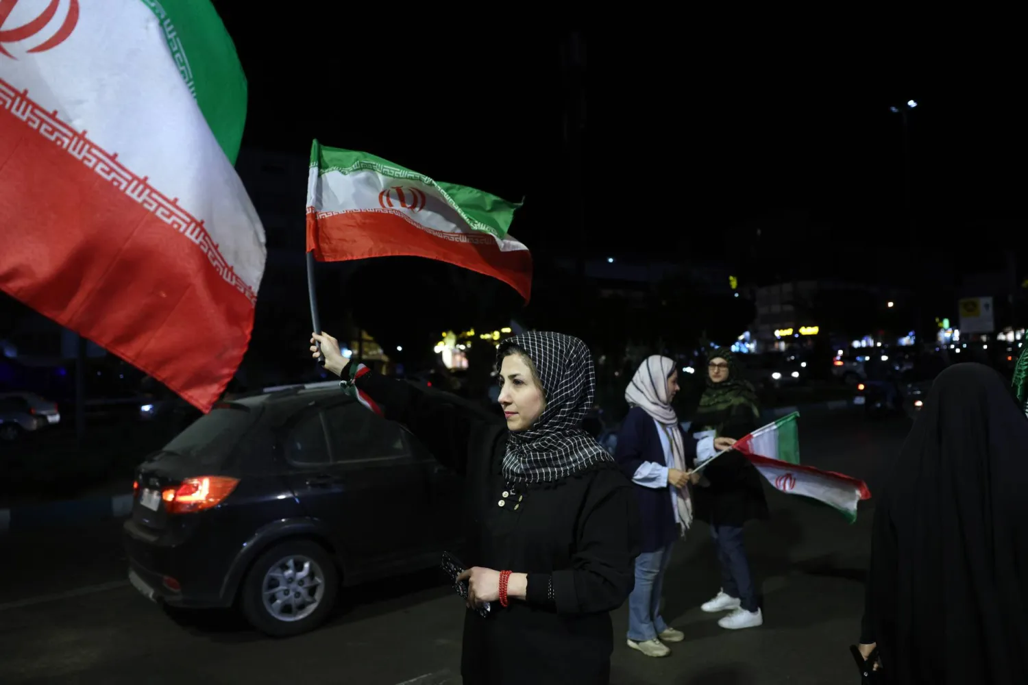 A woman holds Iran’s national flag during a gathering in support of the Iranian government against the US and Israel, in a street in Tehran, Iran, 20 May 2026. EPA/ABEDIN TAHERKENAREH