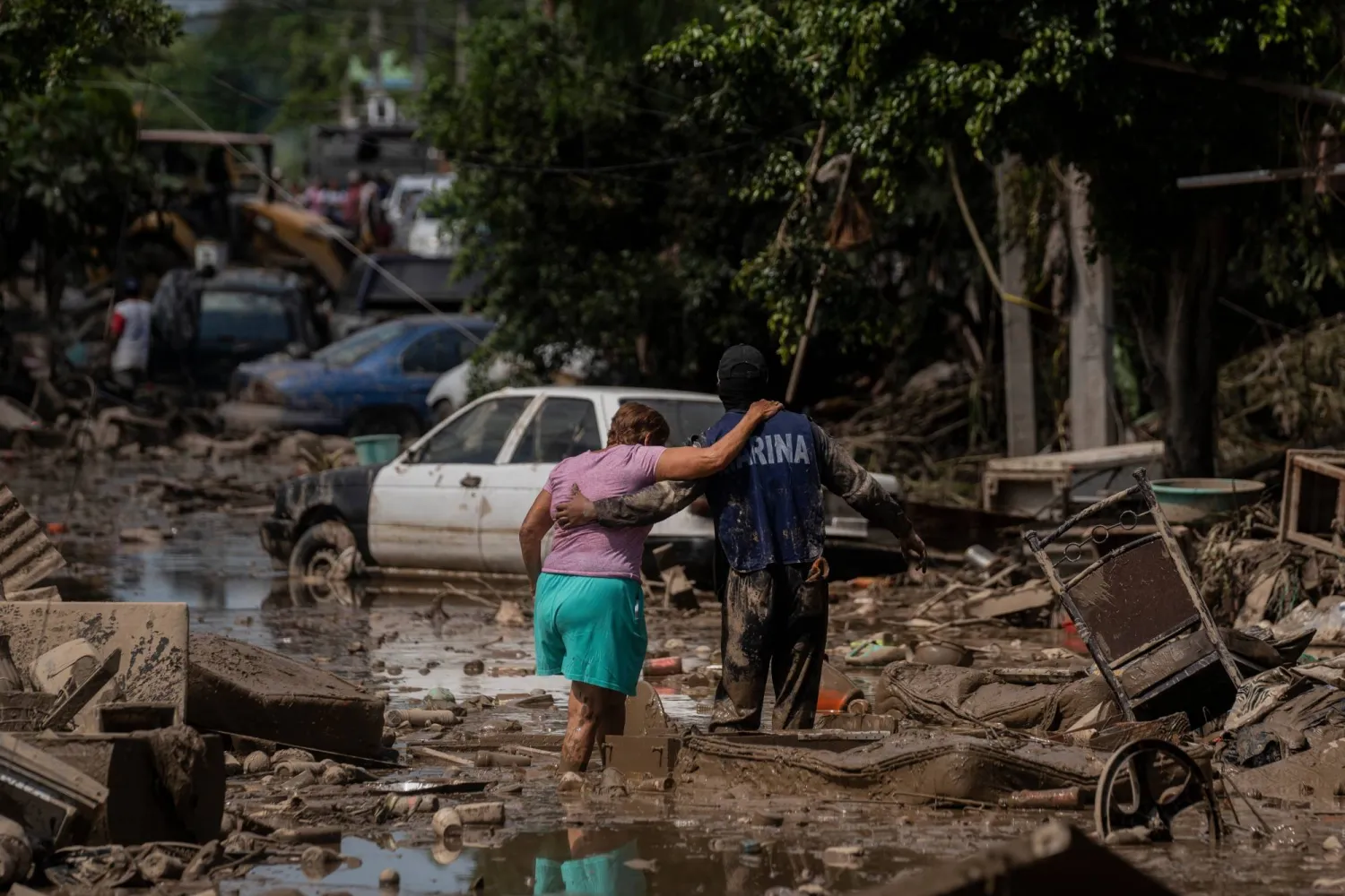 FILE - A Navy officer helps a woman cross a flooded street after heavy rain in Poza Rica, Veracruz state, Mexico, Oct. 12, 2025. (AP Photo/Felix Marquez, File)