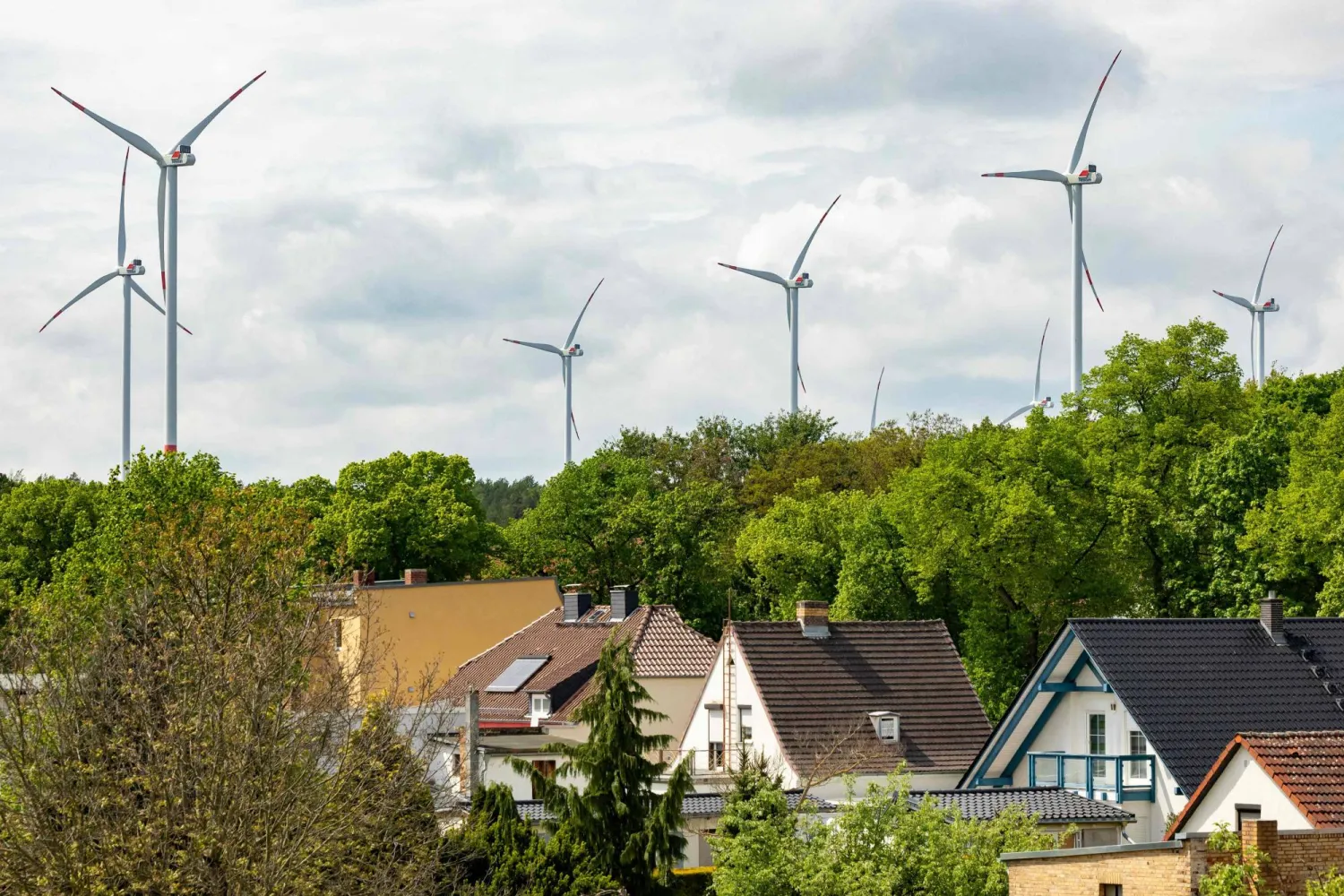 Conventional wind turbines are seen behind houses in Schipkau, eastern Germany on May 13, 2026. (Photo by Odd ANDERSEN / AFP) 
