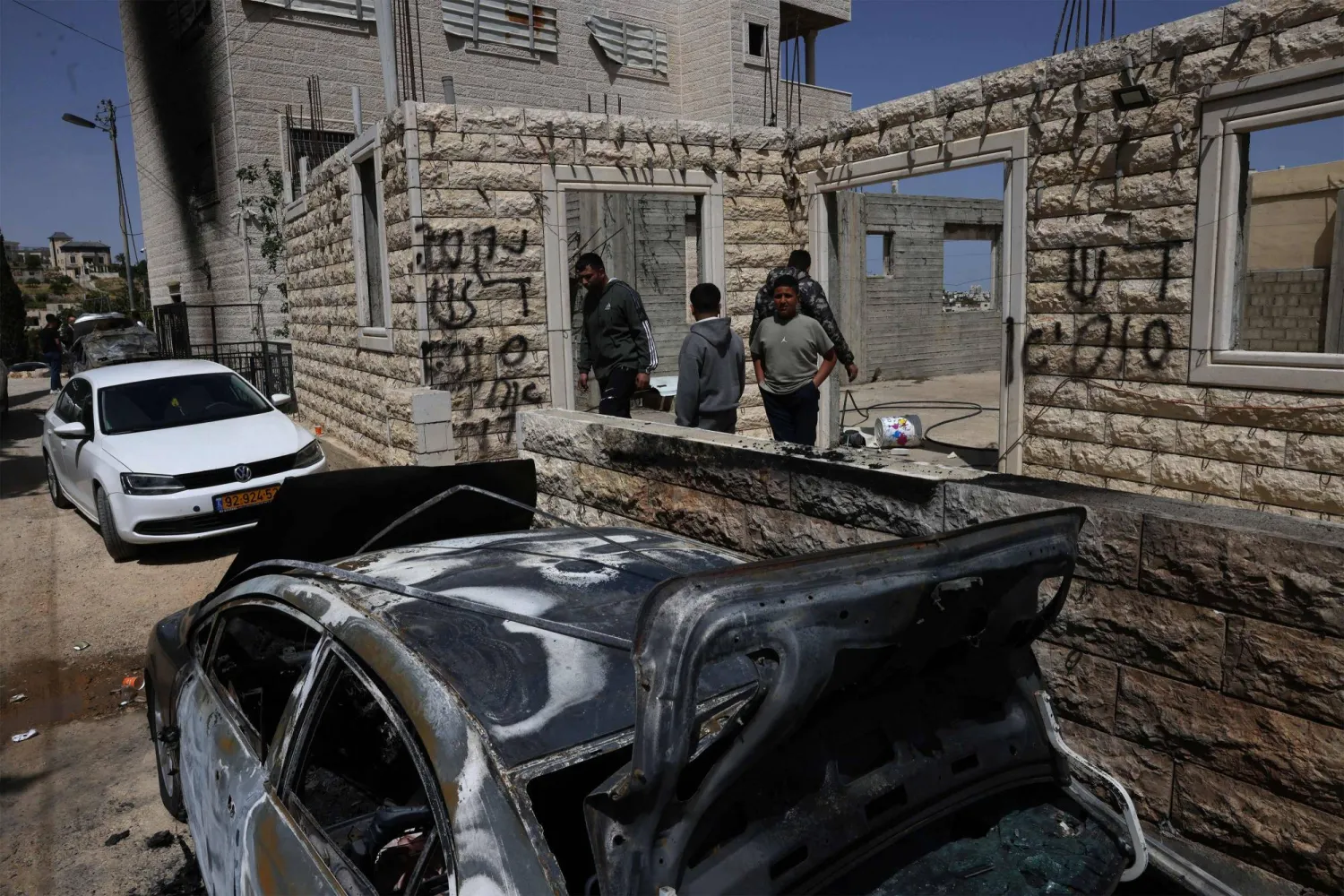 فلسطينيون يتفقدون مركبات مدمرة أمام منازلهم بعد هجوم لمستوطنين قرب مدينة الخليل بالضفة الغربية المحتلة (أ.ف.ب)