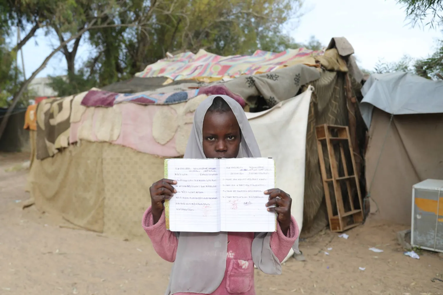 تلميذة سودانية ترفع كراستها أمام فصلها في مدرسة للاجئين في تاجوراء شرق العاصمة الليبية طرابلس يوم 18 مايو 2026 (أ.ب)