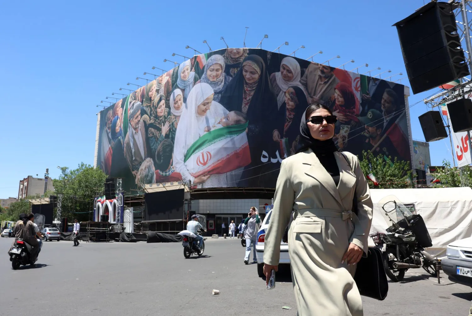 A woman walks next to a huge billboard in a street in Tehran, Iran, 25 May 2026. EPA/ABEDIN TAHERKENAREH